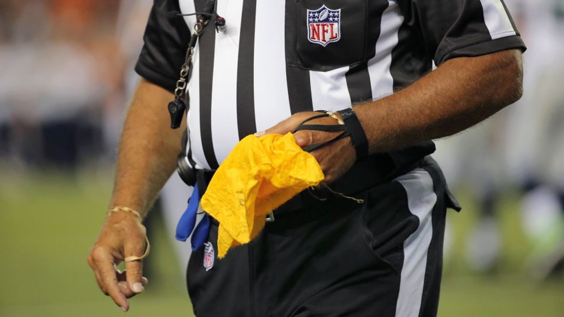 DENVER, CO - AUGUST 07: A referee collects his penalty flag as the Seattle Seahawks face the Denver Broncos during preseason action at Sports Authority Field at Mile High on August 7, 2014 in Denver, Colorado. The Broncos defeated the Seahawks 21-16. (Photo by Doug Pensinger/Getty Images)