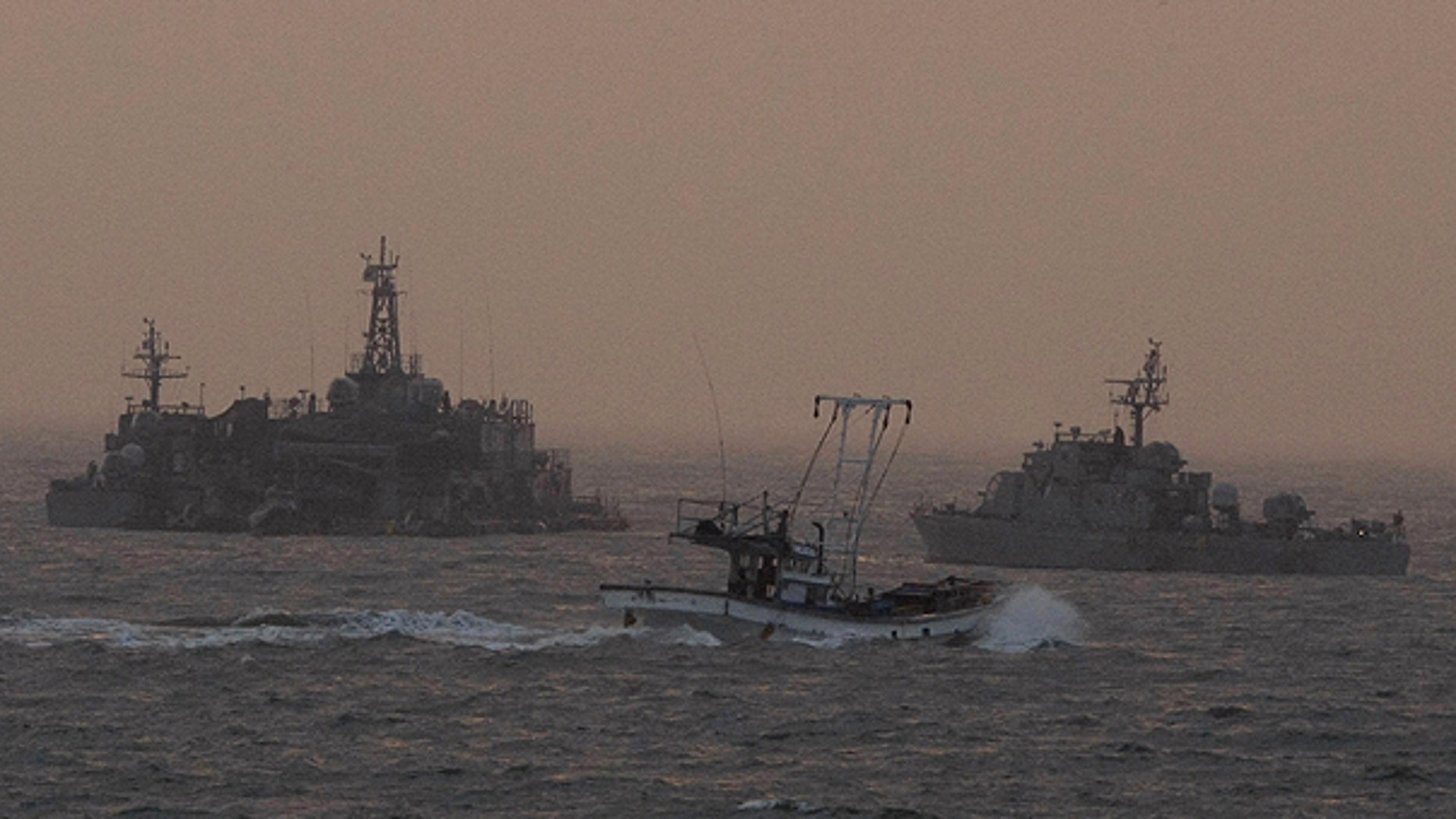 Dec. 19: A South Korean fishing boat sails by a South Korean navy facility and navy ship near Yeonpyeong island, South Korea.