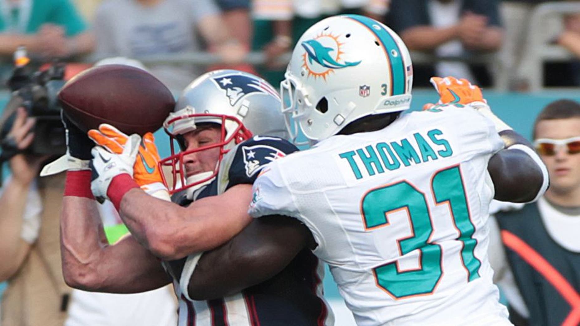 New England Patriots wide receiver Danny Amendola (80) attempts to hold onto the ball as Miami Dolphins Michael Thomas (31) defends during the second half of an NFL football game, Sunday, Dec. 15, 2013, in Miami Gardens, Fla. The Dolphins defeated the Patriots 24-20. (AP Photo/J Pat Carter)