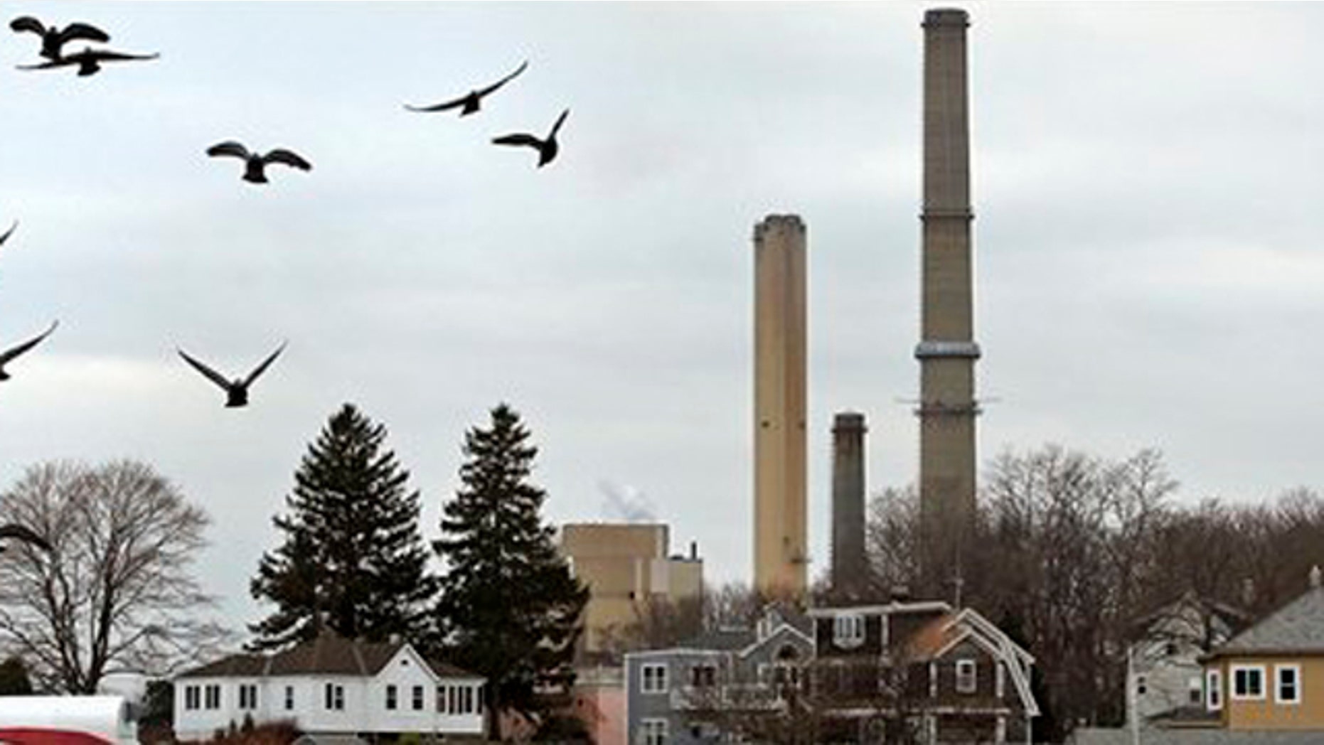 December 14, 2011: Pigeons fly past as the stacks of Dominion's power plant tower over a nearby neighborhood in Salem, Mass.