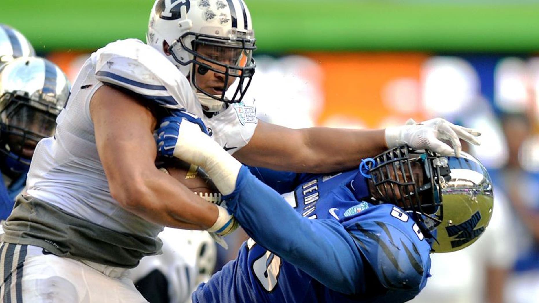 Dec 22, 2014; Miami, FL, USA; Brigham Young Cougars running back Algernon Brown (24) stiff arms Memphis Tigers defensive lineman Terry Redden (56) during the third quarter in the Miami Beach Bowl at Marlins Park. Memphis won 55-48 in a double overtime. Mandatory Credit: Steve Mitchell-USA TODAY Sports