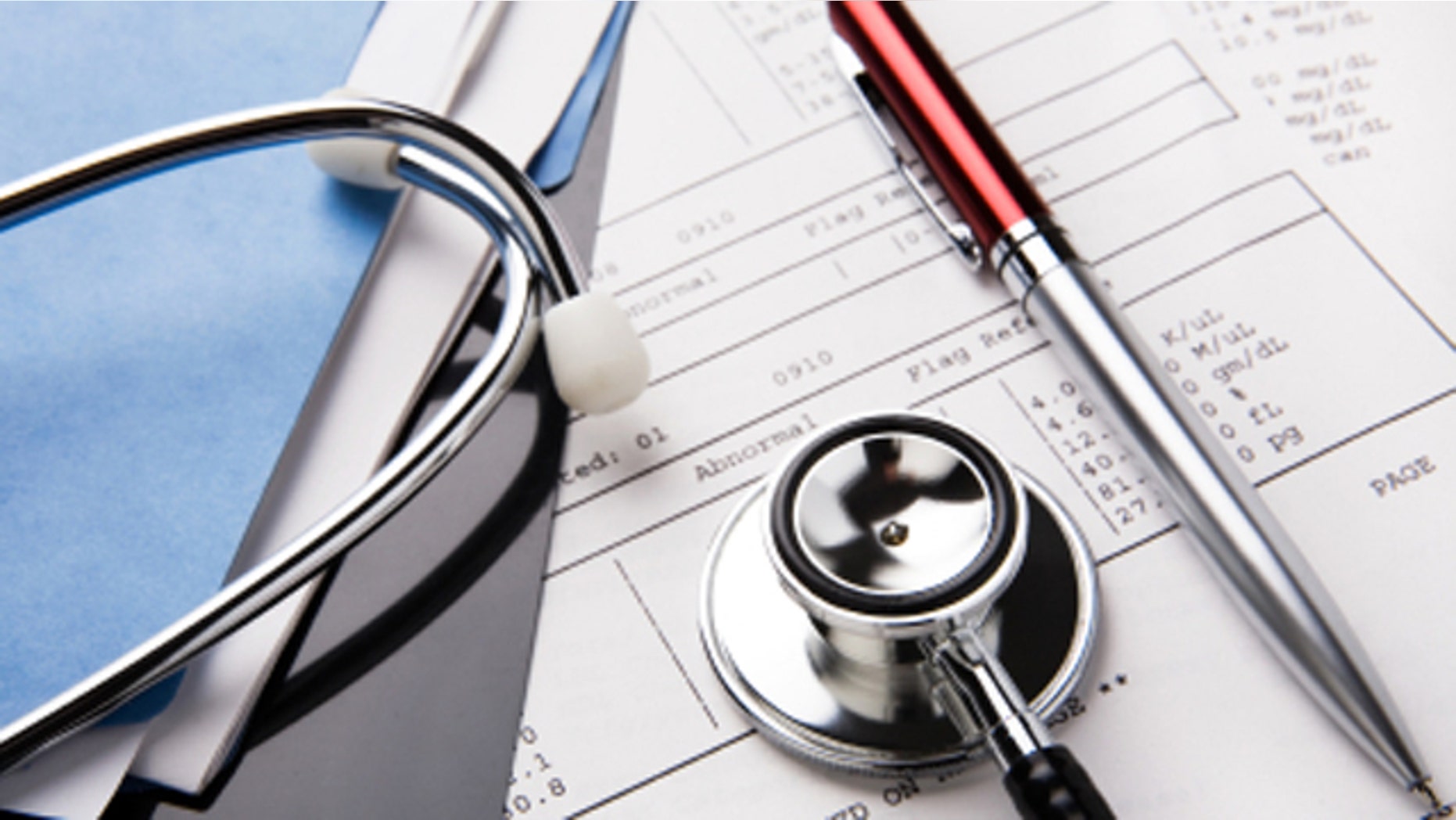 stethoscope and pen resting on a sheet of medical lab test results, with patient file and x-ray or mri film