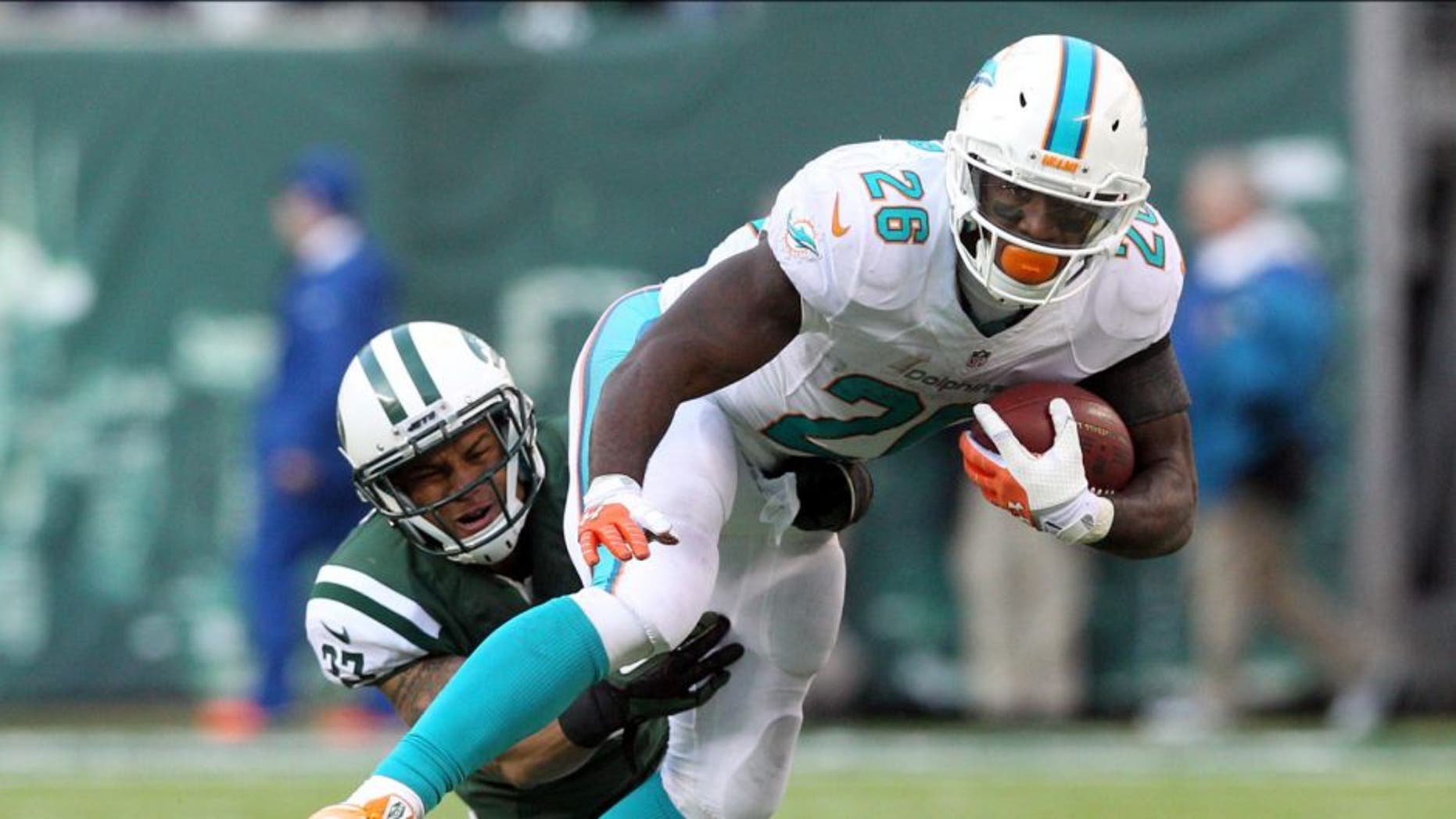 Dec 1, 2013; East Rutherford, NJ, USA; Miami Dolphins running back Lamar Miller (26) breaks a tackle by New York Jets corner back Dee Milliner (27) during the third quarter of a game at MetLife Stadium. The Dolphins defeated the Jets 23-3. Mandatory Credit: Brad Penner-USA TODAY Sports