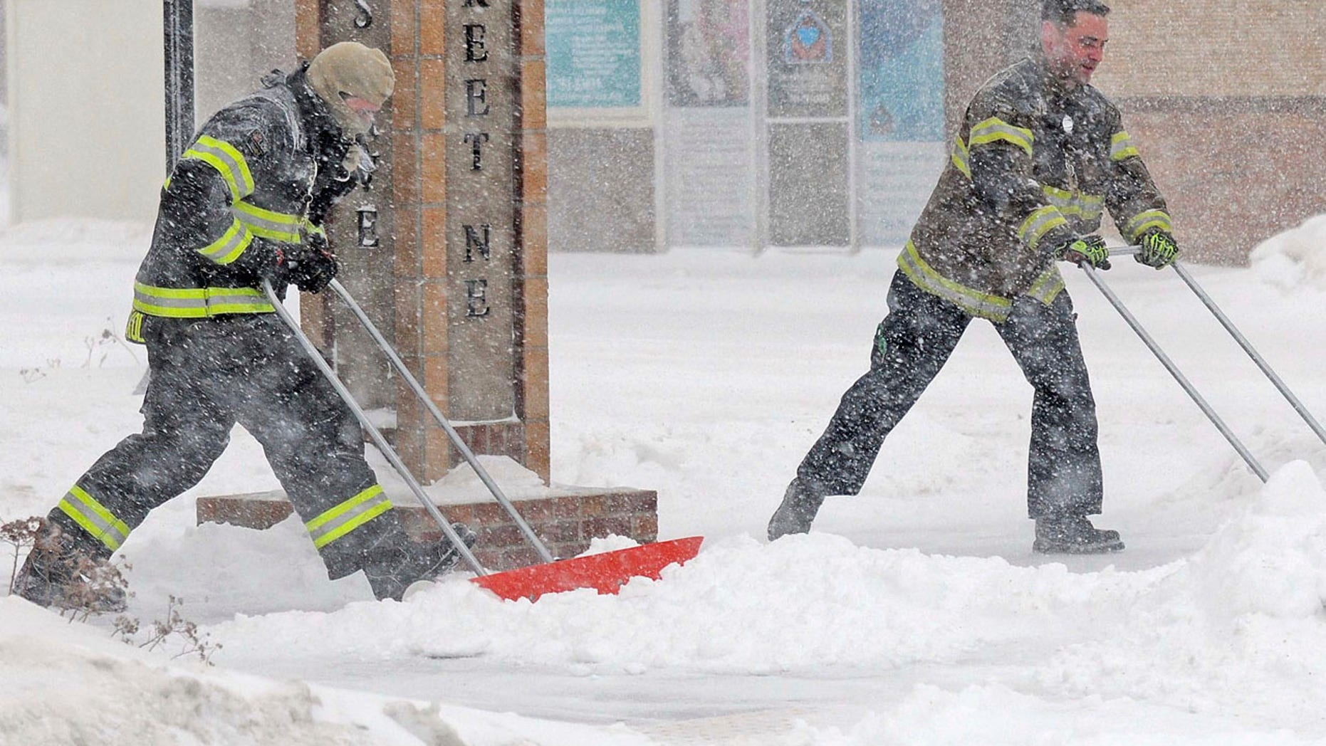 Dec. 25, 2016: Mandan firefighters Shane Weltikol, left, and Chad Nicklos clear accumulating snow from outside the firehouse in downtown Mandan, N.D., as the Christmas Day blizzard intensifies.