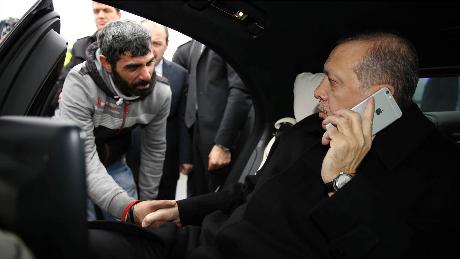 Dec. 25, 2015: Turkish President Recep Tayyip Erdogan, right, takes Vezir Cakras by hand while speaking on his mobile phone inside his car stationed over the Bosporus Bridge in Istanbul.