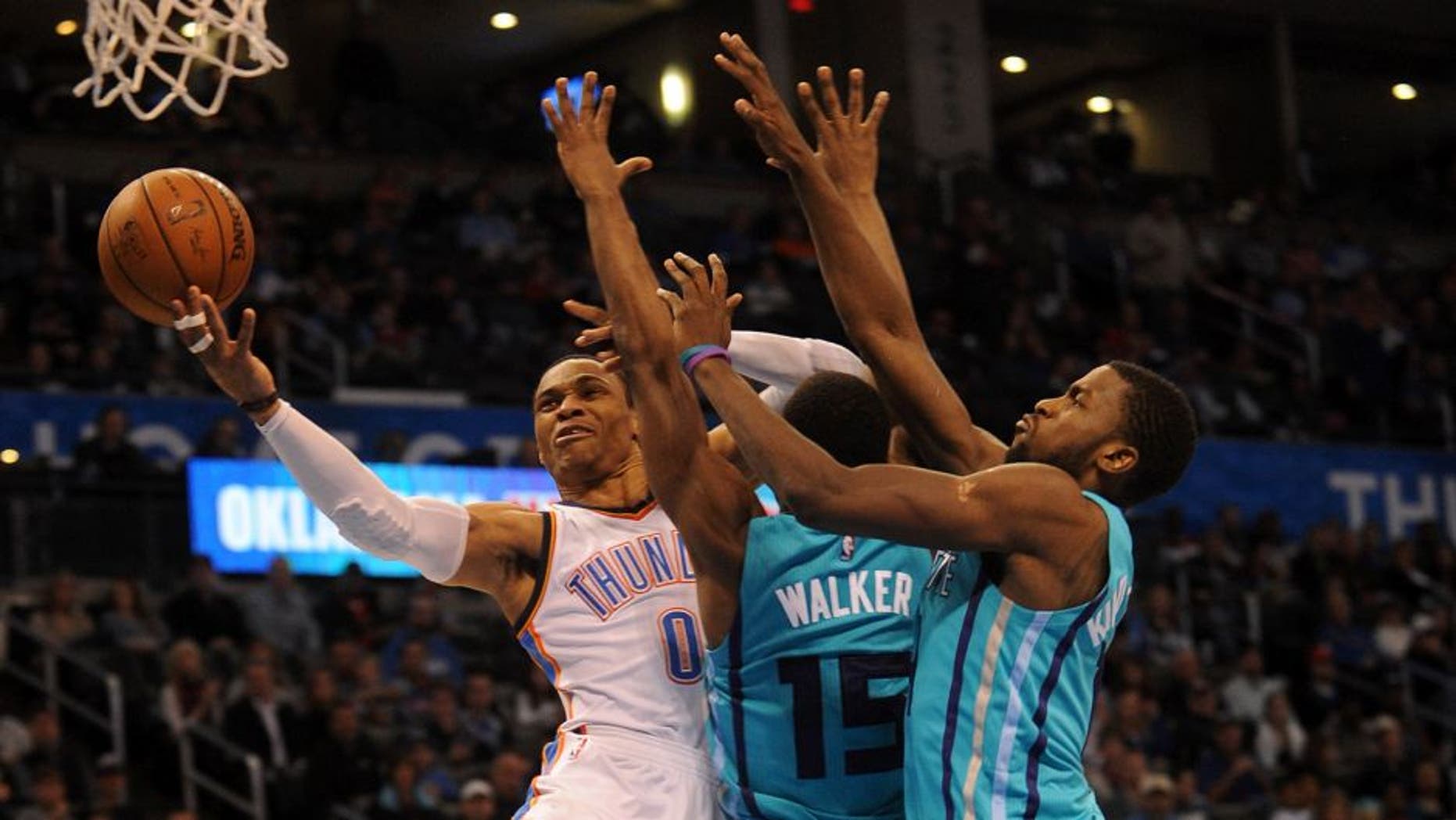 Dec 26, 2014; Oklahoma City, OK, USA; Oklahoma City Thunder guard Russell Westbrook (0) attempts a shot against Charlotte Hornets forward Michael Kidd-Gilchrist (14) and Hornets guard Kemba Walker (15) during the third quarter at Chesapeake Energy Arena. Mandatory Credit: Mark D. Smith-USA TODAY Sports