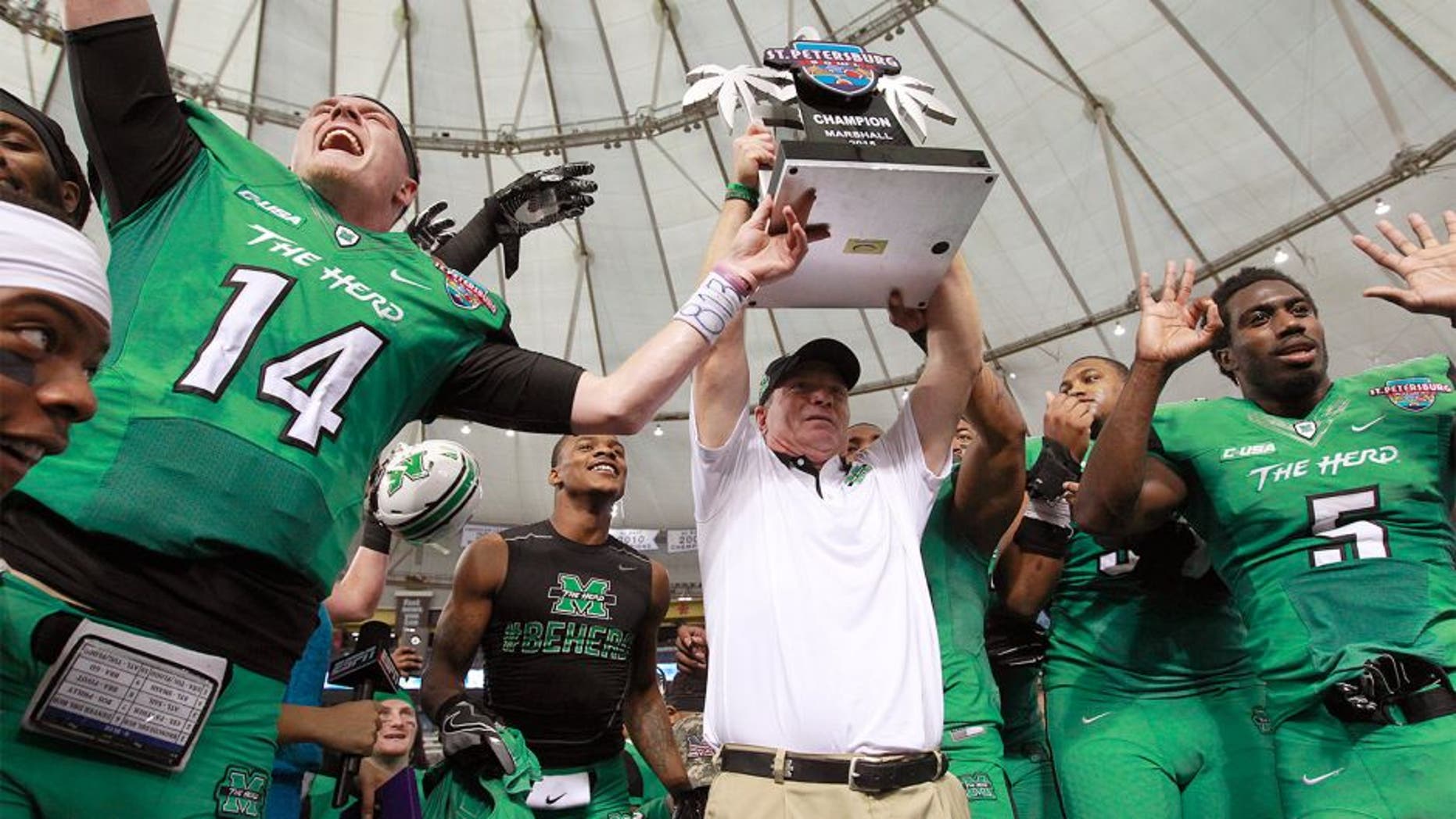 Dec 26, 2015; St. Petersburg, FL, USA; Marshall Thundering Herd head coach Doc Holliday raises the trophy with teammates after they beat the Connecticut Huskies to win the St. Petersburg Bowl at Tropicana Field. Marshall Thundering Herd defeated the Connecticut Huskies 16-10. Mandatory Credit: Kim Klement-USA TODAY Sports
