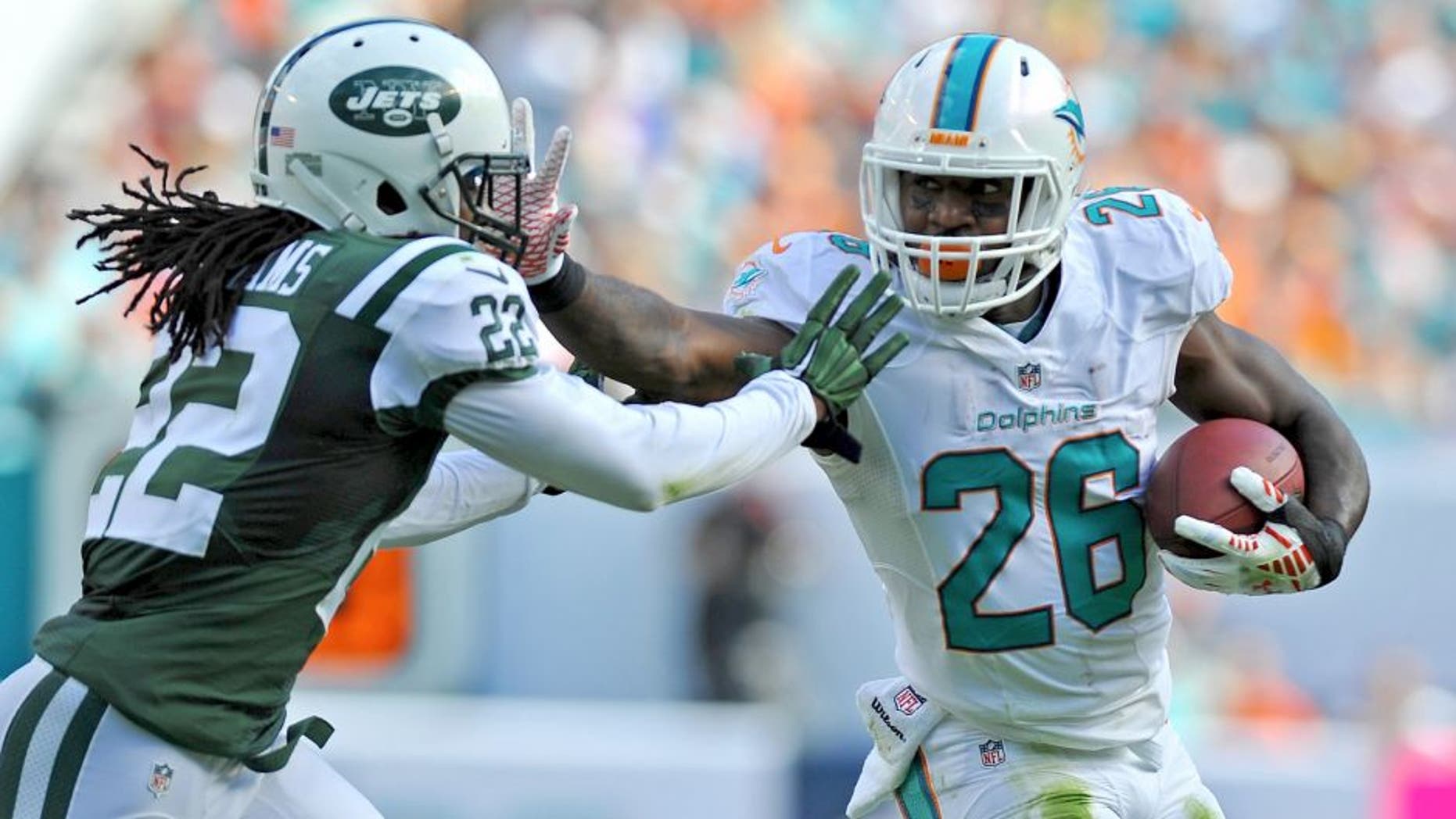 Dec 28, 2014; Miami Gardens, FL, USA; Miami Dolphins running back Lamar Miller (26) stiff arms New York Jets cornerback Marcus Williams (22) during the first half at Sun Life Stadium. Mandatory Credit: Steve Mitchell-USA TODAY Sports