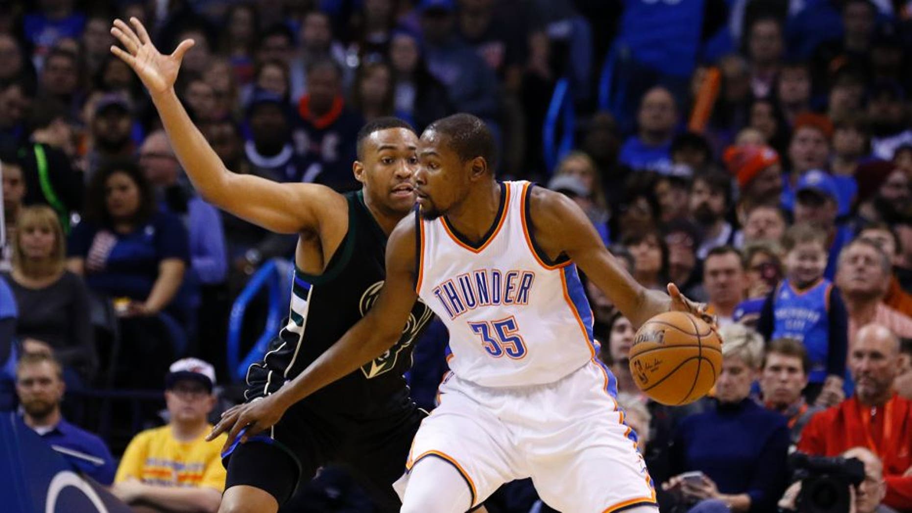 Milwaukee Bucks guard Khris Middleton, left, defends as Oklahoma City Thunder forward Kevin Durant (35) drives to the basket during the first quarter of an NBA basketball game in Oklahoma City, Tuesday, Dec. 29, 2015. (AP Photo/Alonzo Adams)