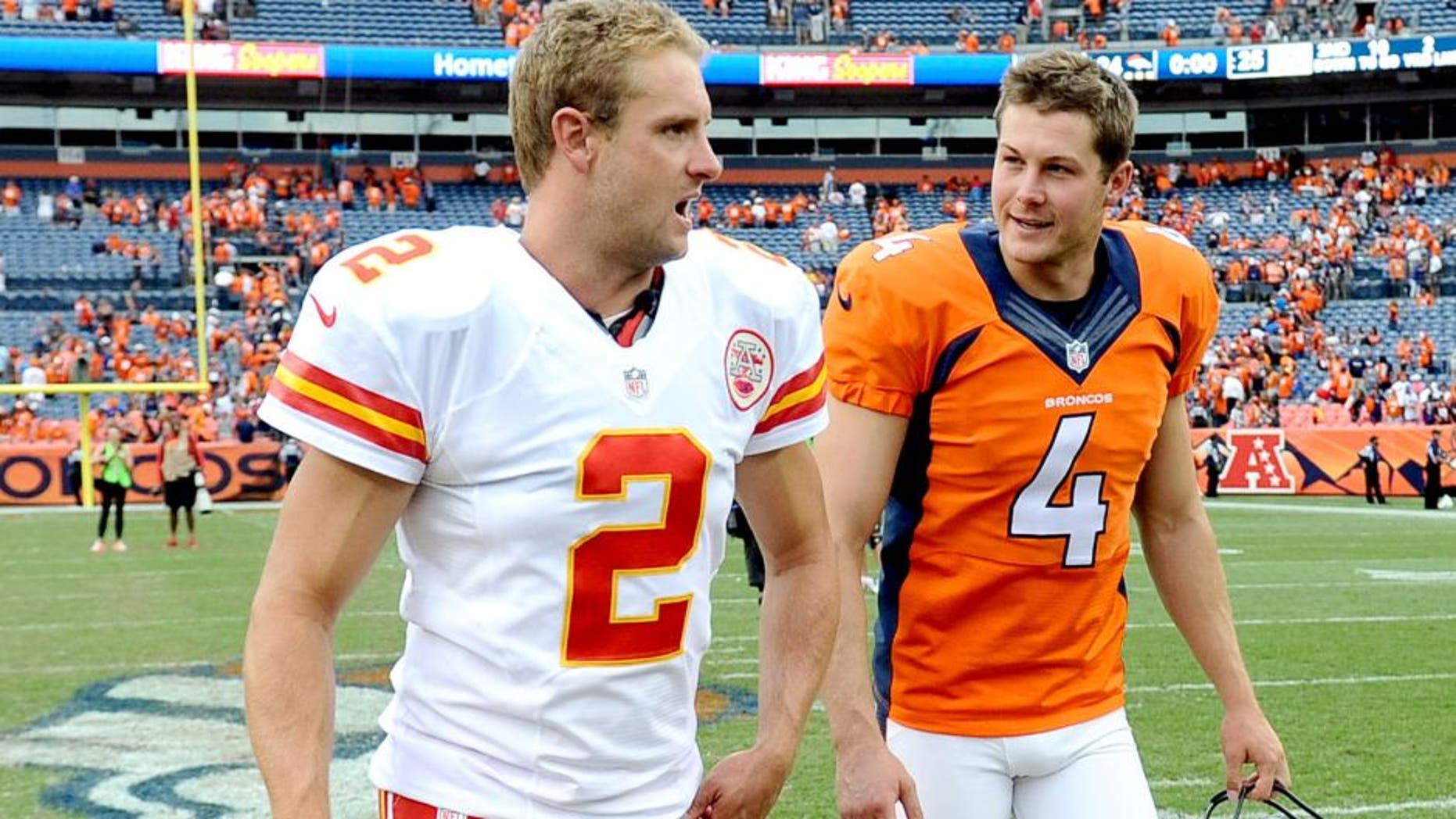 Sep 14, 2014; Denver, CO, USA; Kansas City Chiefs punter Dustin Colquitt (2) and Denver Broncos punter Britton Colquitt (4) talk following the game at Sports Authority Field at Mile High. The Broncos defeated the Chiefs 24-17. Mandatory Credit: Ron Chenoy-USA TODAY Sports