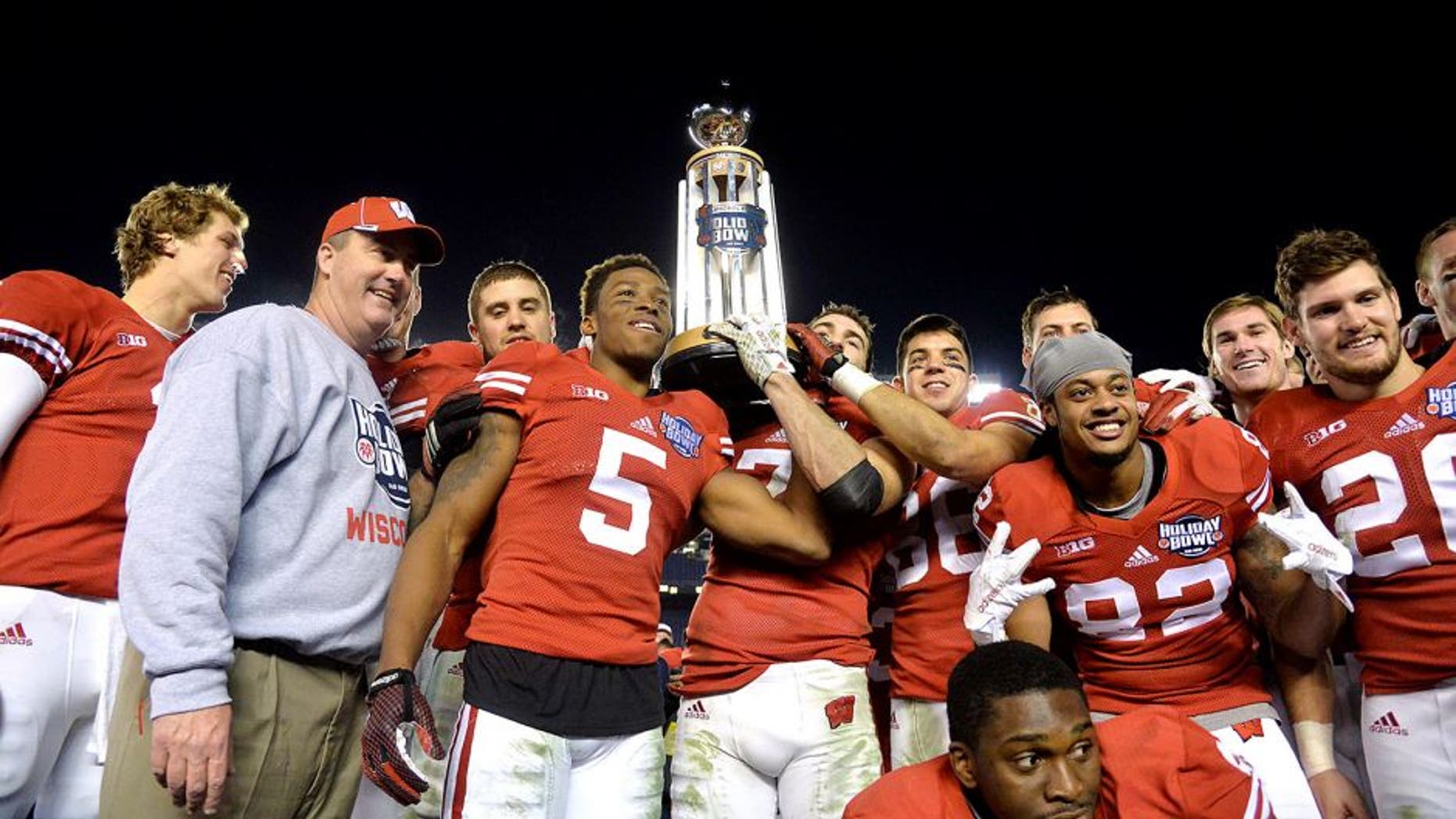 Dec 30, 2015; San Diego, CA, USA;Wisconsin Badgers players and head coach Paul Chryst hoist the championship trophy after the 2015 Holiday Bowl against the Southern California Trojans at Qualcomm Stadium. Wisconsin defeated USC 23-21. Mandatory Credit: Kirby Lee-USA TODAY Sports