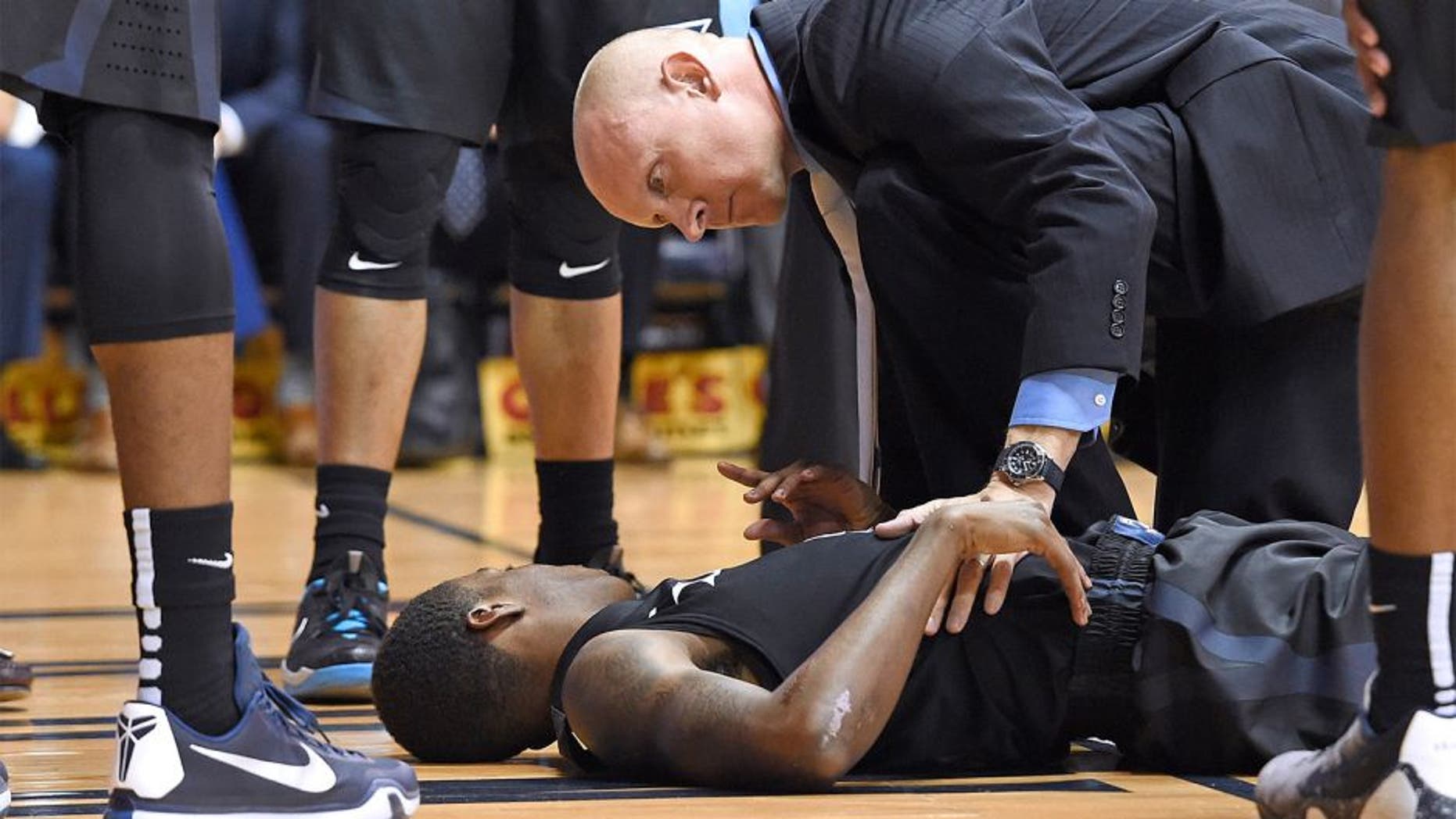 Dec 31, 2015; Villanova, PA, USA; Xavier Musketeers guard Edmond Sumner (4) is checked on by head coach Chris Mack (R) after being injured against the Villanova Wildcats during the first half at The Pavilion. Mandatory Credit: Eric Hartline-USA TODAY Sports