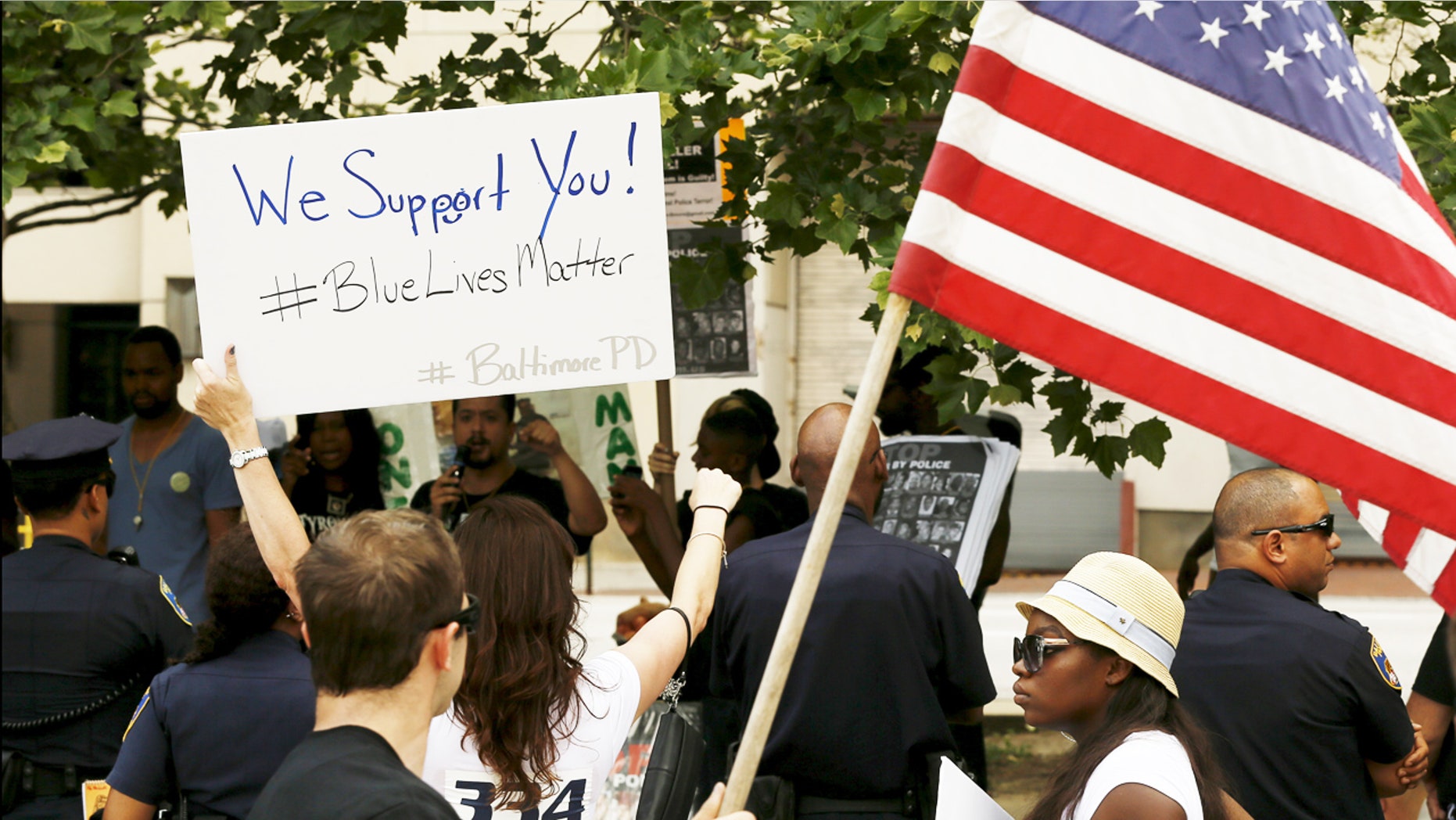 Police supporters (front) and counter demonstrators (rear) yell at each other as they are separated by a line of police during a Blue Lives Matter rally in support of the Baltimore police in front of City Hall in Baltimore, Maryland.