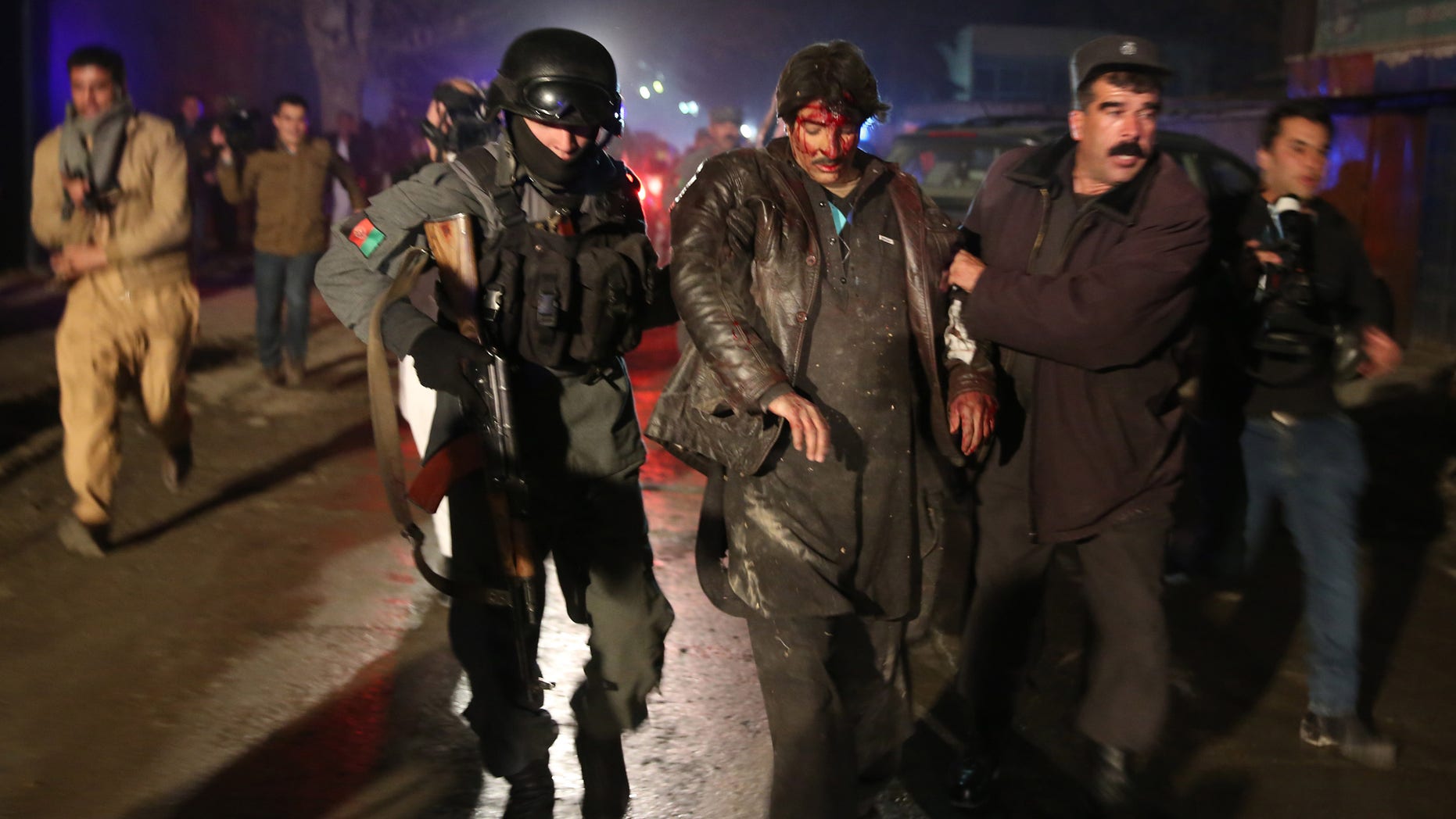 Afghan police forces assist an injured man at the site of an explosion in Kabul, Afghanistan, Friday, Jan. 17, 2014. Afghan police said a suicide bomber attacked a Kabul restaurant popular with foreigners, officials. (AP Photo/Massoud Hossaini)