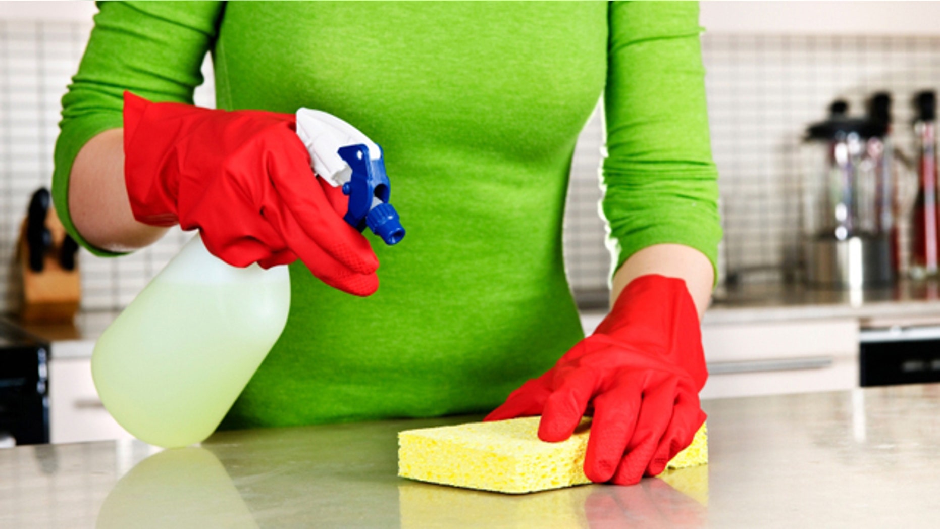 Girl cleaning kitchen with sponge and rubber gloves