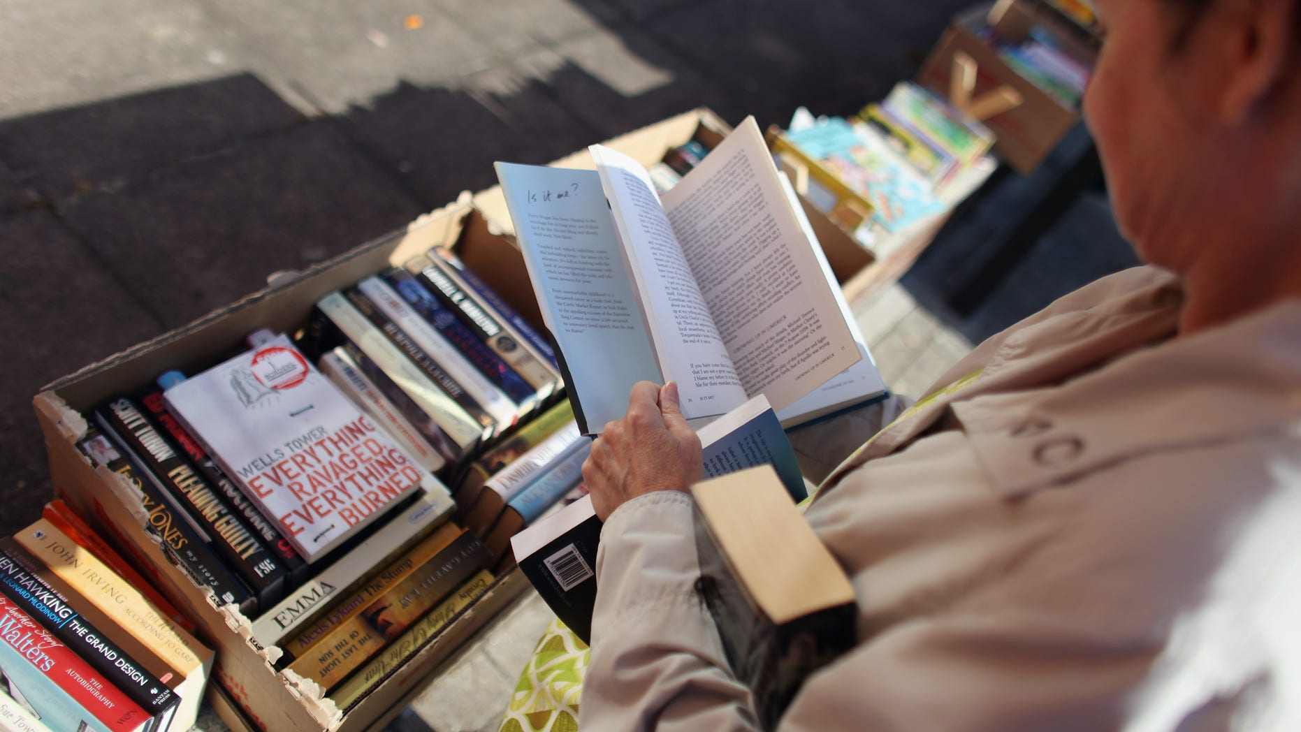 LONDON, ENGLAND - OCTOBER 14: A woman looks through donated books which are available for free loan outside Kensal Rise library, which is threatened with closure, and where activists and local residents are holding a vigil to prevent it from being boarded up on October 14, 2011 in London, England. A judge has ruled that Brent council can shut six of its 12 libraries, creating a precedent for other local authorities in England and Wales to reduce their expenditure in similar fashion.> on October 14, 2011 in London, England. (Photo by Oli Scarff/Getty Images)