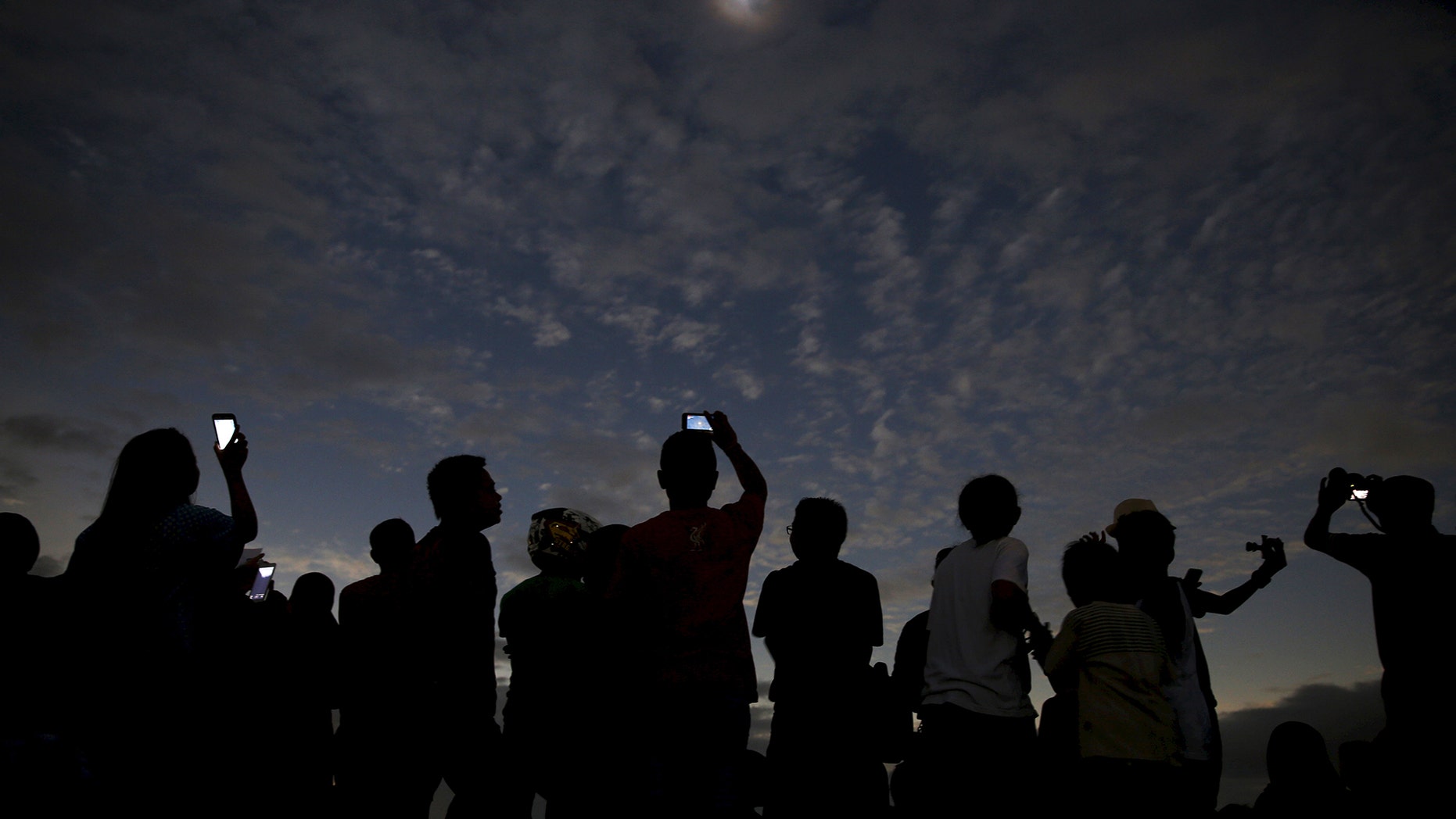 People watch and take pictures of the solar eclipse at the beach on Ternate island, Indonesia, March 9, 2016. REUTERS/Beawiharta TPX IMAGES OF THE DAY - RTS9XDW