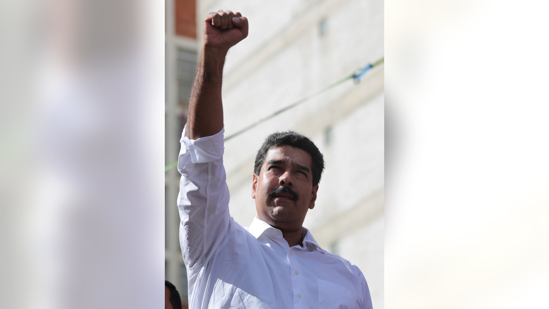 In this photo provided by Miraflores Presidential Press Office, Venezuela's President Nicolas Maduro holds up fist in solidarity at a transport workers rally in Caracas, Venezuela, Tuesday, Nov. 12, 2013. Maduro says he'll present evidence in the coming hours showing how the U.S. Embassy in Caracas is plotting to destabilize the South American nation. Maduro's announcement at a pro-government rally Tuesday comes after he vowed to extend price caps that have led to long lines of bargain hunters at appliance stores across the country in recent days. (AP Photo/Miraflores Presidential Office)