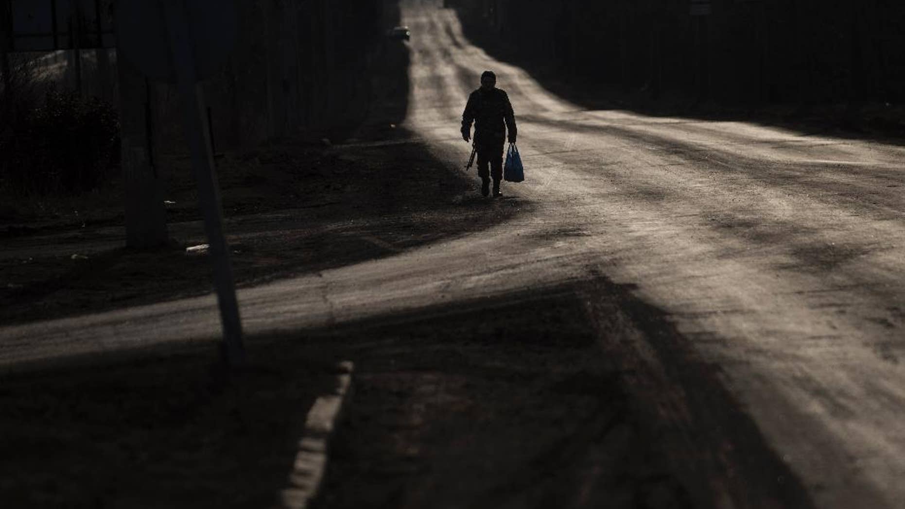 A Ukrainian serviceman walks on an empty road near Artemivsk, eastern Ukraine, Friday, March 6, 2015. Ukrainian military officials say government forces are withdrawing heavy rocket launchers from the front line with Russian-backed separatists in accordance with last month's cease-fire accord. (AP Photo/Evgeniy Maloletka)