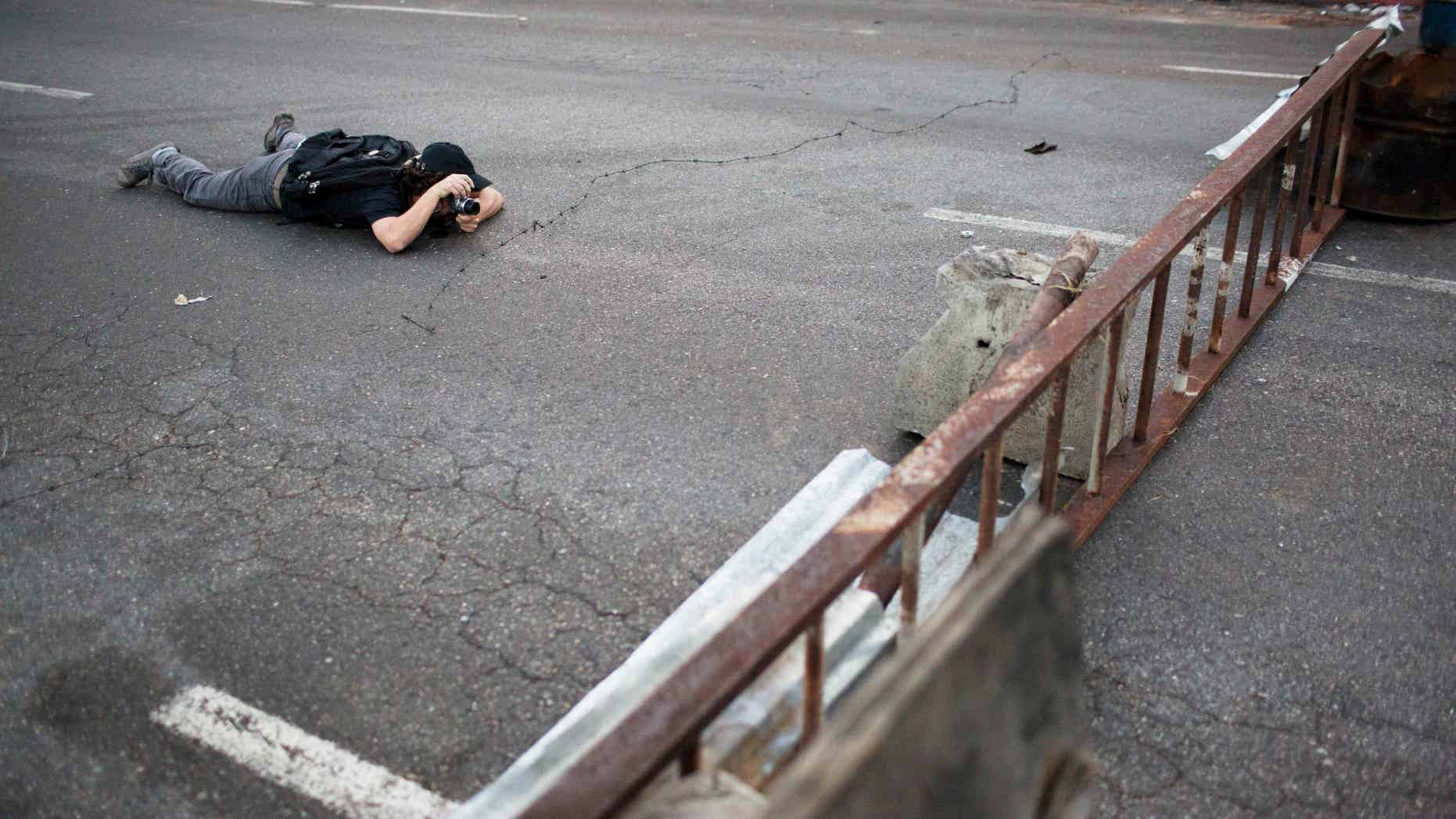 A photographer takes pictures of barricades set up by anti-government protesters in the Altamira neighborhood of Caracas, Venezuela, Thursday, Feb. 20, 2014. Violence is heating up in Venezuela as an opposition leader faces criminal charges for organizing a rally that set off escalating turmoil in the oil-rich, but economically struggling country. (AP Photo/Rodrigo Abd)