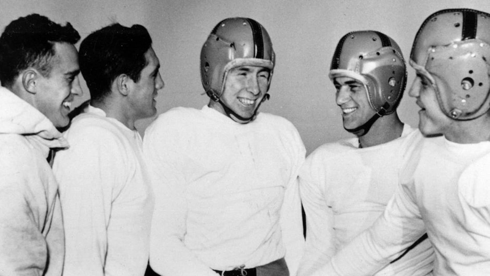 FILE - In this Dec. 11, 1953, file photo, Notre Dame player John Lattner, center, winner of the 1953 Heisman tropy and second-time winner of the Maxwell trophy, receives congratulations from teammates at practice in South Bend, Ind. Lattner, who helped lead Notre Dame to a 9-0-1 record and a No. 2 ranking in Frank Leahy's final year as coach, has died at 83. His death was confirmed Saturday, Feb. 13, 2016, by Notre Dame. (AP Photo/File)