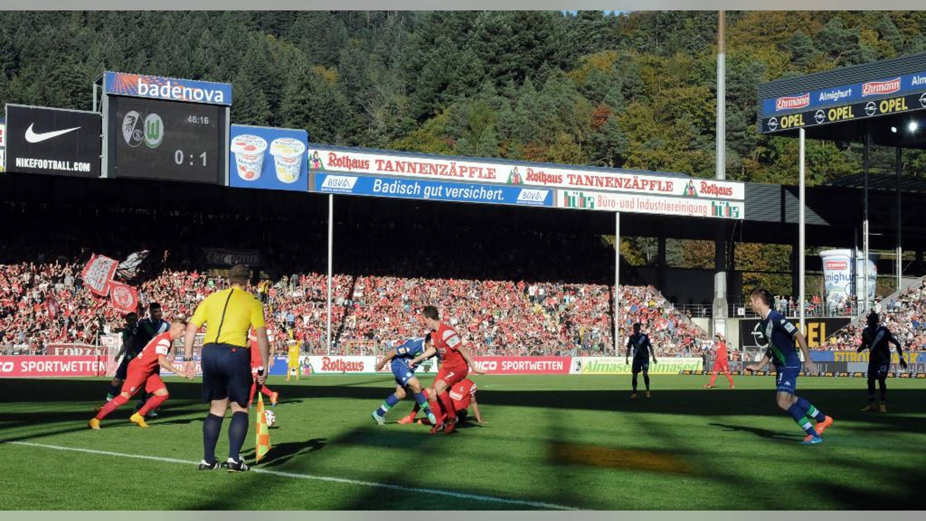 In this photo taken Saturday, Oct. 18, 2014, Freiburg, playing in red, face Wolfsburg in a Bundesliga soccer match in Freiburg, Germany. As one of the Bundesliga’s most financially disadvantaged teams, Freiburg deploys an array of coping strategies to stay in Germany’s top division and remain competitive against rivals like Wolfsburg that have richer resources, revenues and budgets. (AP Photo/John Leicester)