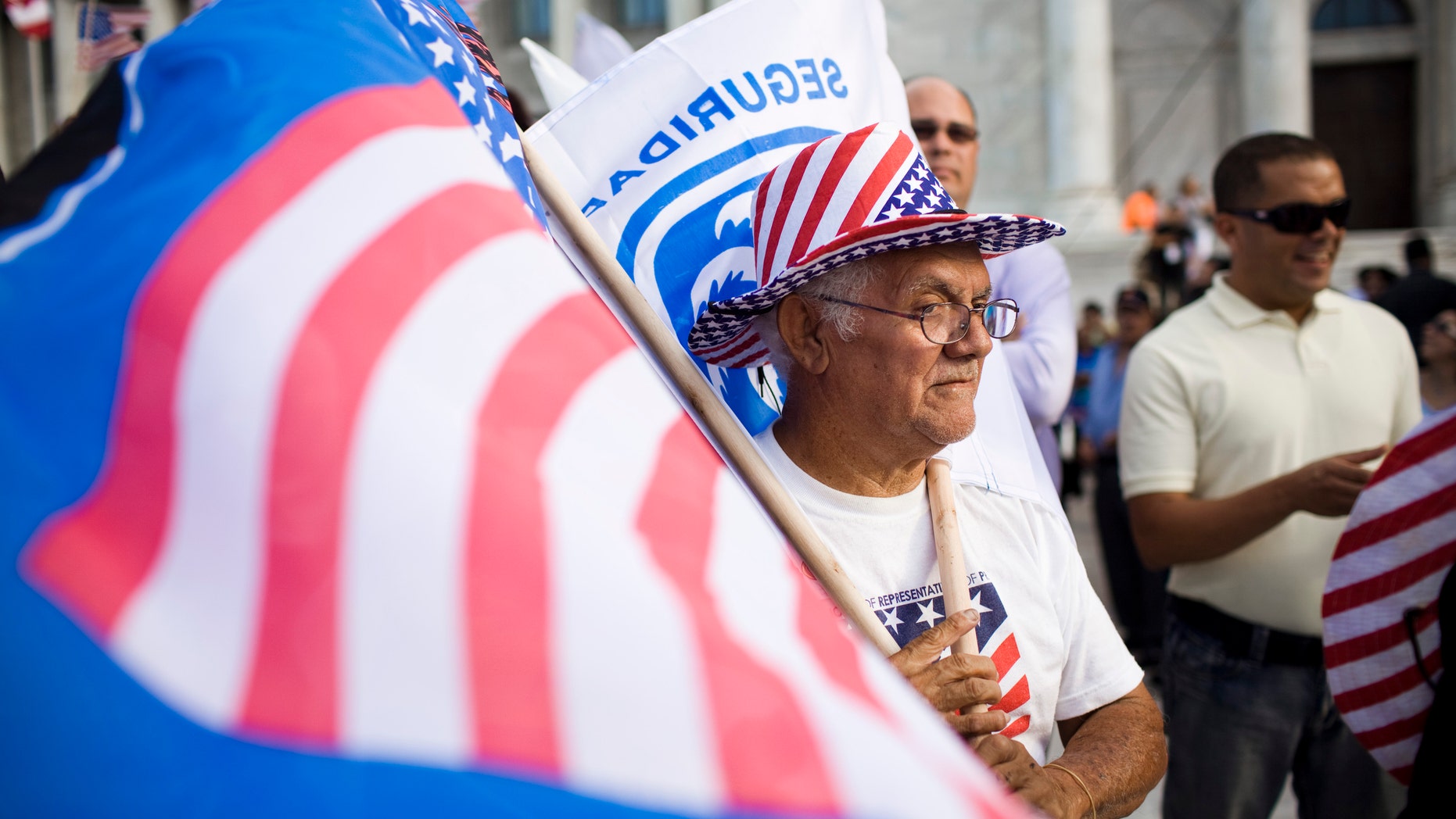 SAN JUAN, PUERTO RICO - MARCH 16:
Roberto Maldonado, 75, sells flags at a New Progressive Party rally where Republican presidential candidate, former Massachusetts Gov. Mitt Romney was campaigning on the North Side of the Capitol building March 16, 2012 in San Juan, Puerto Rico. Luis Fortuno, the island's governor and a Republican, has already expressed his support for the former governor for president. Romney's two-day campaign on the island is meant to win the 23 GOP delegates up for grabs on the U.S. territory. Romney's fiscal views are likely to resonate with the island's large private sector. (Photo by Christopher Gregory/Getty Images)