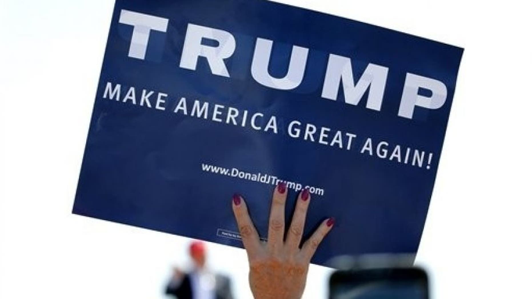 In this March 19, 2016 file photo, a supporter holds a sign as Republican presidential candidate Donald Trump speaks during a campaign rally in Fountain Hills, Ariz.