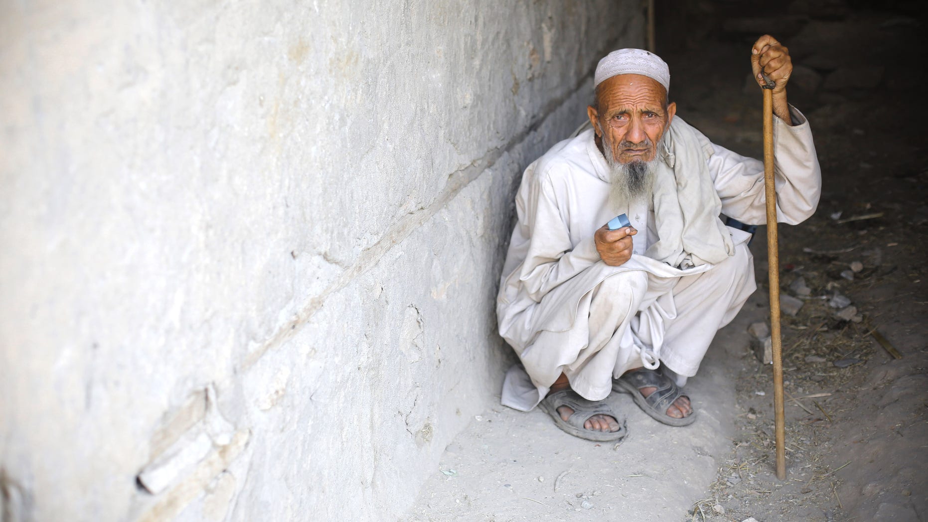 An elderly man takes cover during a firefight between Afghan soldiers and insurgents on June 15, 2012 in the Pech Valley, Afghanistan.