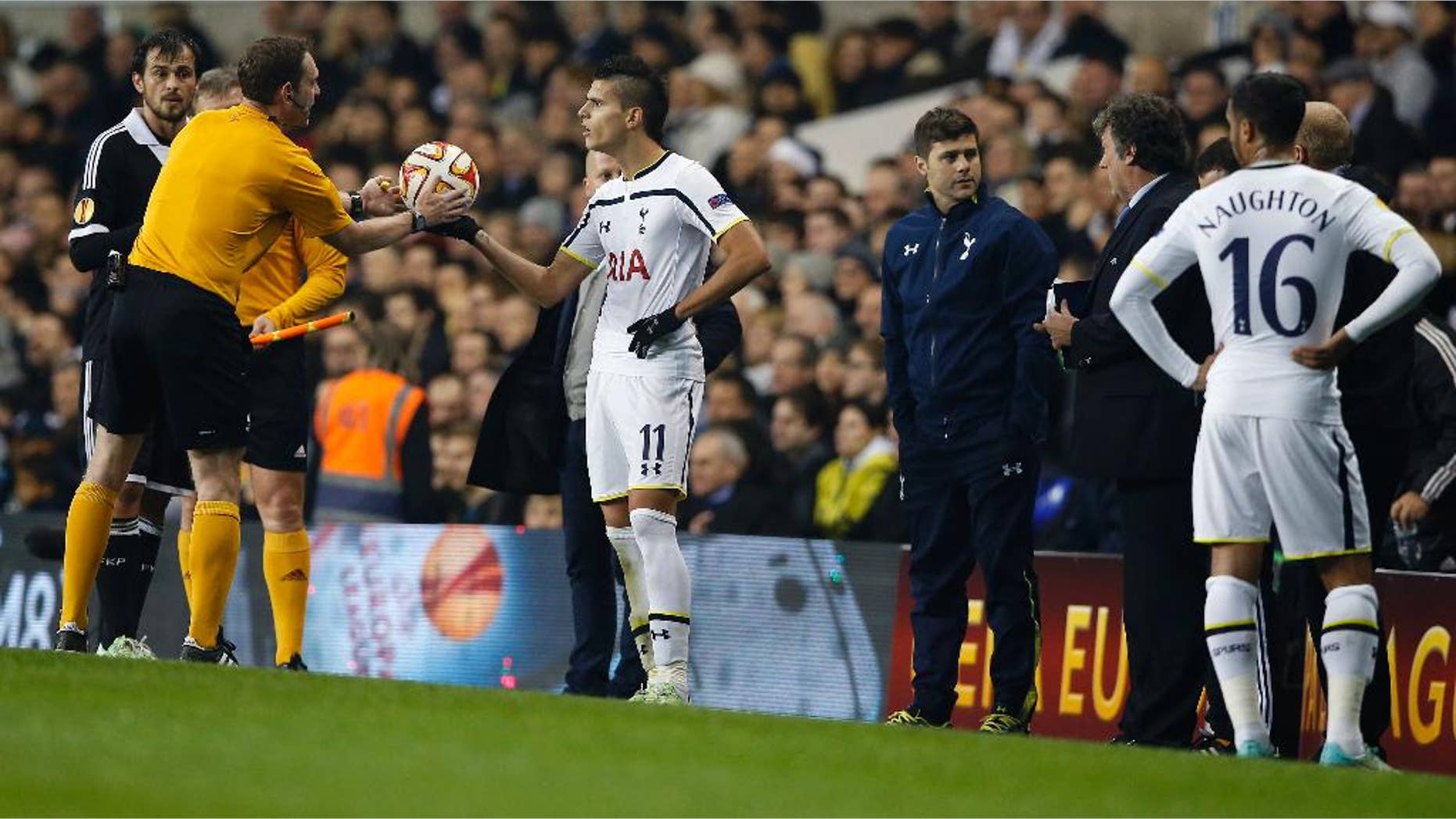 The referee Yevhen Aranovsky takes the ball from Tottenham's Erik Lamela as he halts the match after three separate pitch invasions during the Europa League group C soccer match between Tottenham Hotspur and Partizan Belgrade at White Hart Lane stadium in London, Thursday, Nov. 27, 2014 .(AP Photo/Alastair Grant)