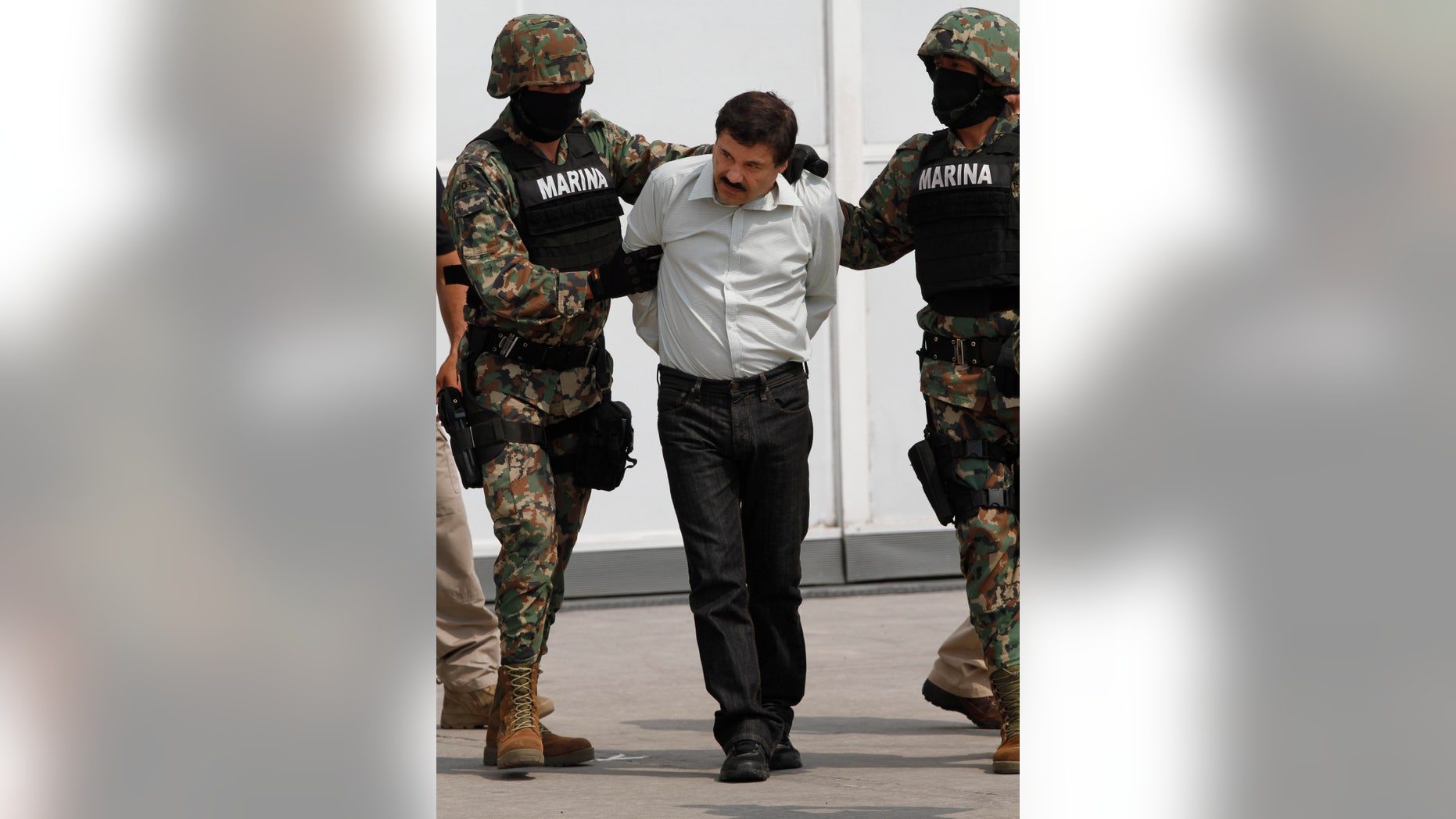 Joaquin "El Chapo" Guzman is escorted to a helicopter in handcuffs by Mexican navy marines at a navy hanger in Mexico City, Saturday, Feb. 22, 2014. A senior U.S. law enforcement official said Saturday, that Guzman, the head of Mexicoís Sinaloa Cartel, was captured alive overnight in the beach resort town of Mazatlan. Guzman faces multiple federal drug trafficking indictments in the U.S. and is on the Drug Enforcement Administrationís most-wanted list. (AP Photo/Marco Ugarte)
