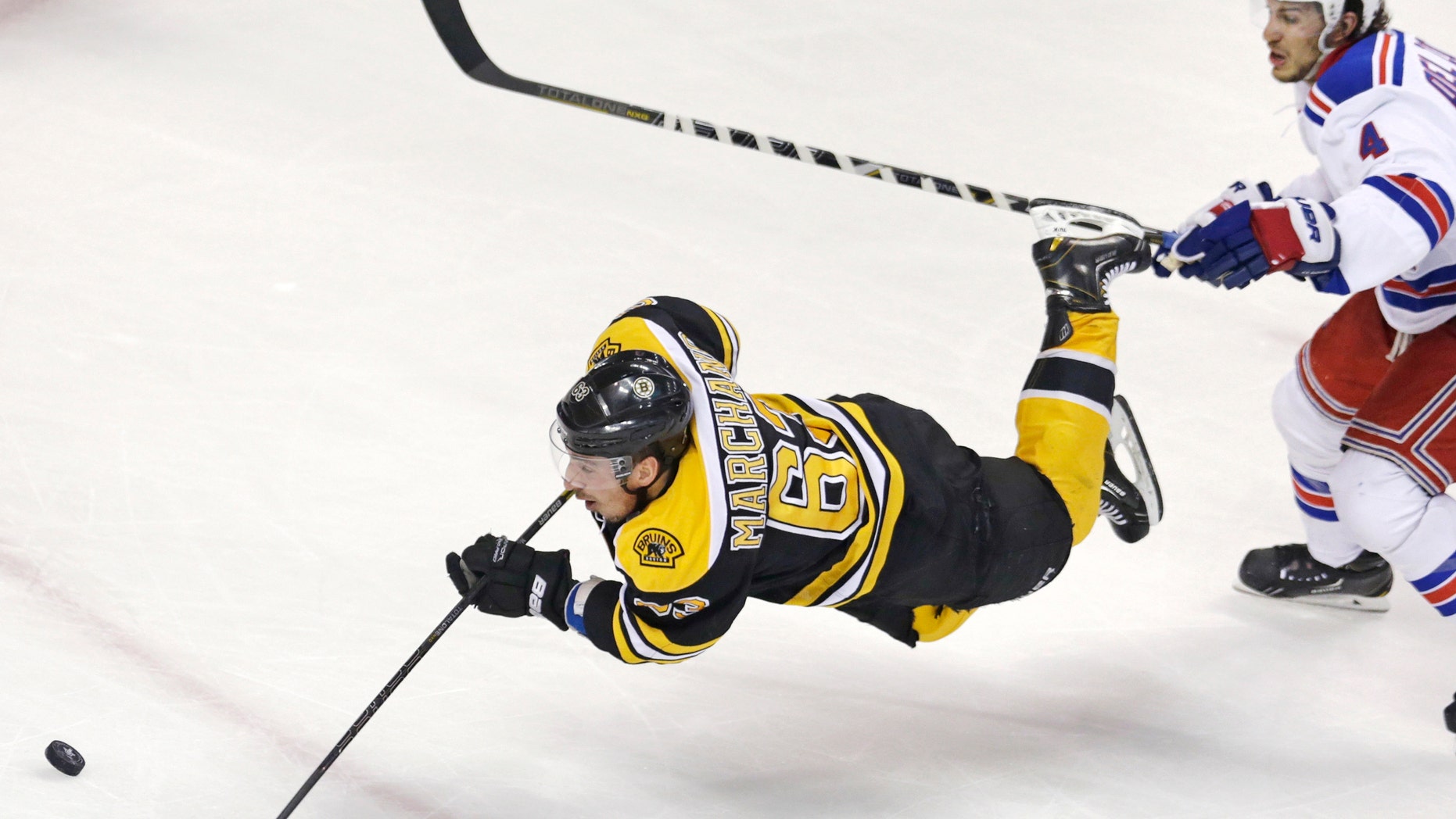 Boston Bruins left wing Brad Marchand (63) is tripped as he shoots on-goal after getting past New York Rangers defenseman Michael Del Zotto (4) during the second period in Game 1 of an NHL hockey playoffs Eastern Conference semifinal game in Boston, Thursday, May 16, 2013. (AP Photo/Charles Krupa)