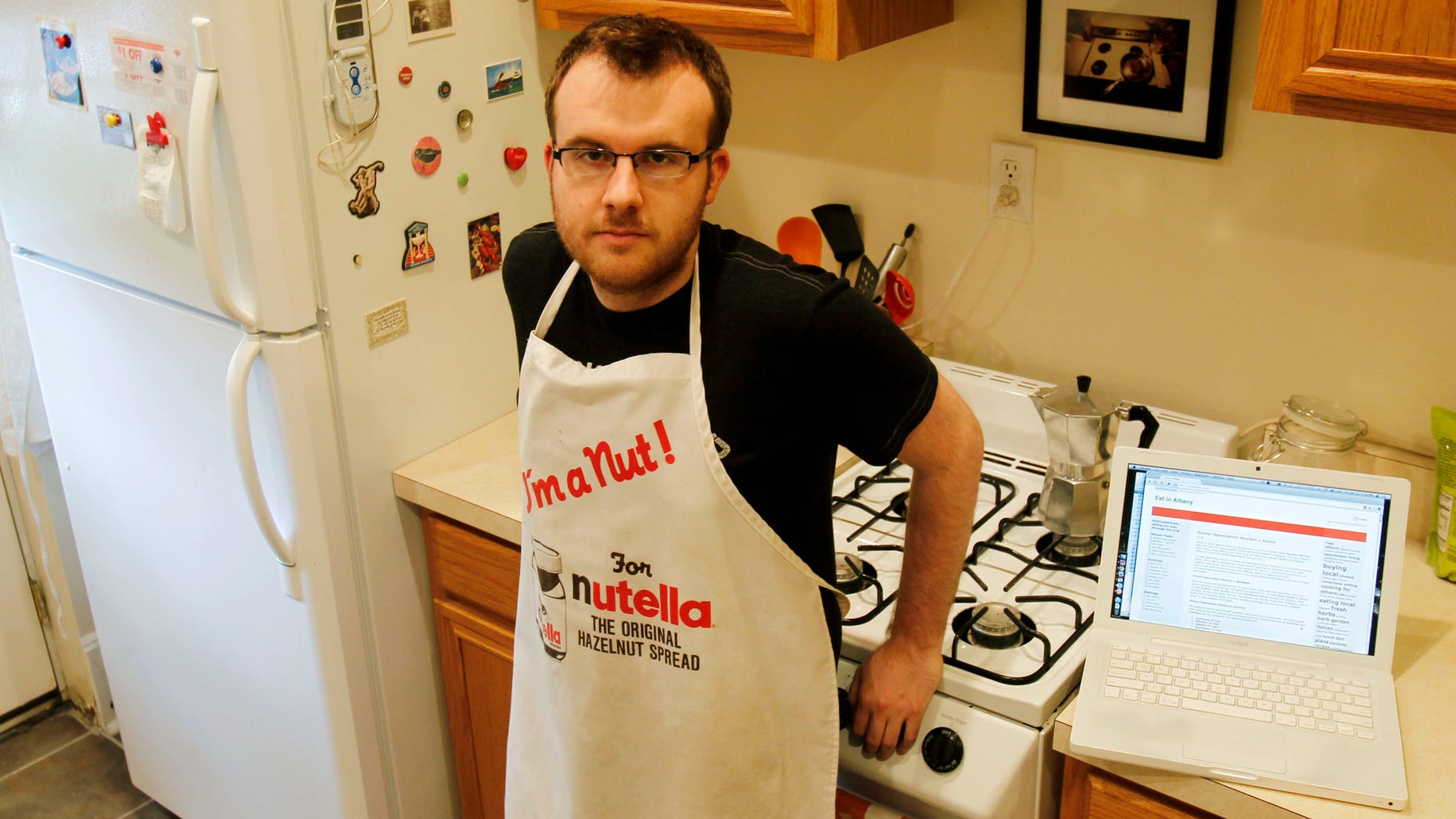 Brian Kraus, who hosts a food blog, poses in his kitchen in Albany, N.Y., on Friday, April 30, 2010. Kraus loves to cook but has only one cookbook. When Kraus wanted tips on preparing a whole fish, he headed to the Web and did a "mishmash" of stuff he liked from different sites. (AP Photo/Mike Groll)
