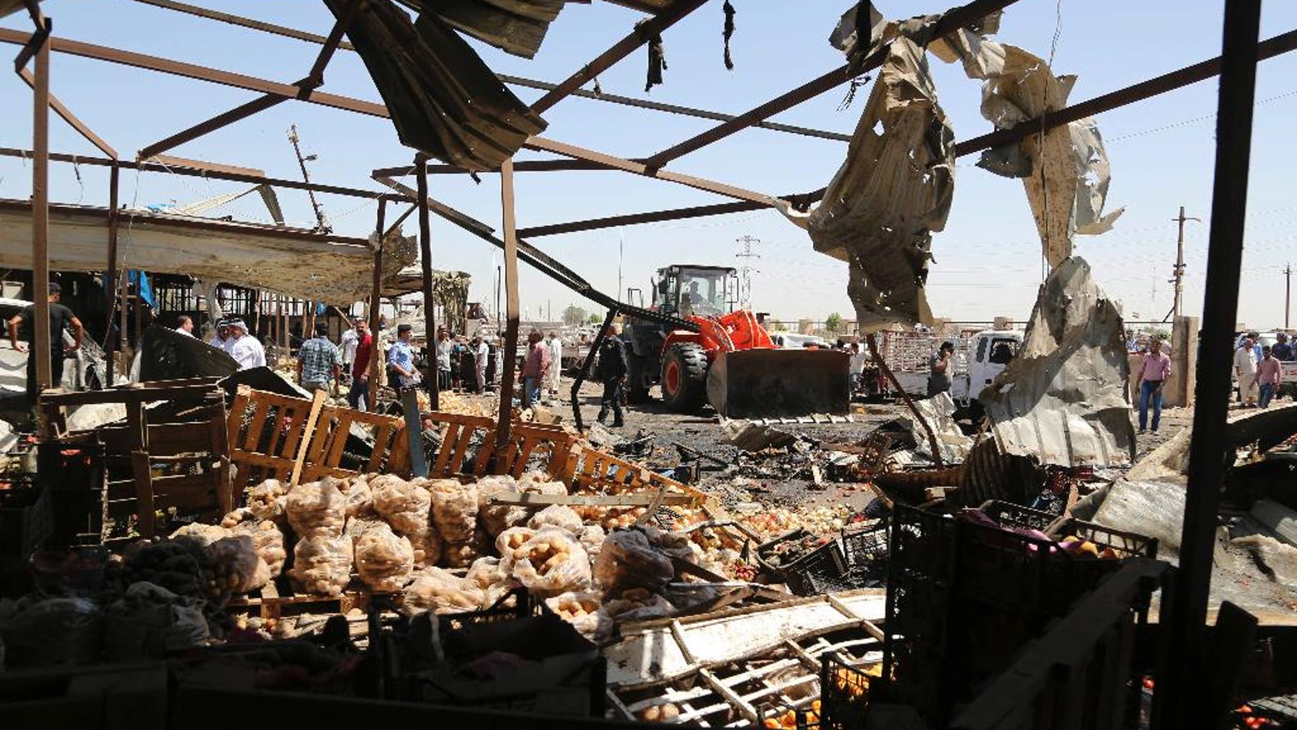 A bulldozer clears rubble at the scene of a deadly suicide car bombing at an outdoor vegetable and fruit market in a Shiite-dominated district in northeastern Baghdad, Iraq, Tuesday, July 12, 2016. The bomb on Tuesday, killed at least 10 people and injured tens of others, officials said. The developments came on the heels of two large-scale attacks claimed by the Islamic State group that killed more than 300 people last week. (AP Photo/Karim Kadim)