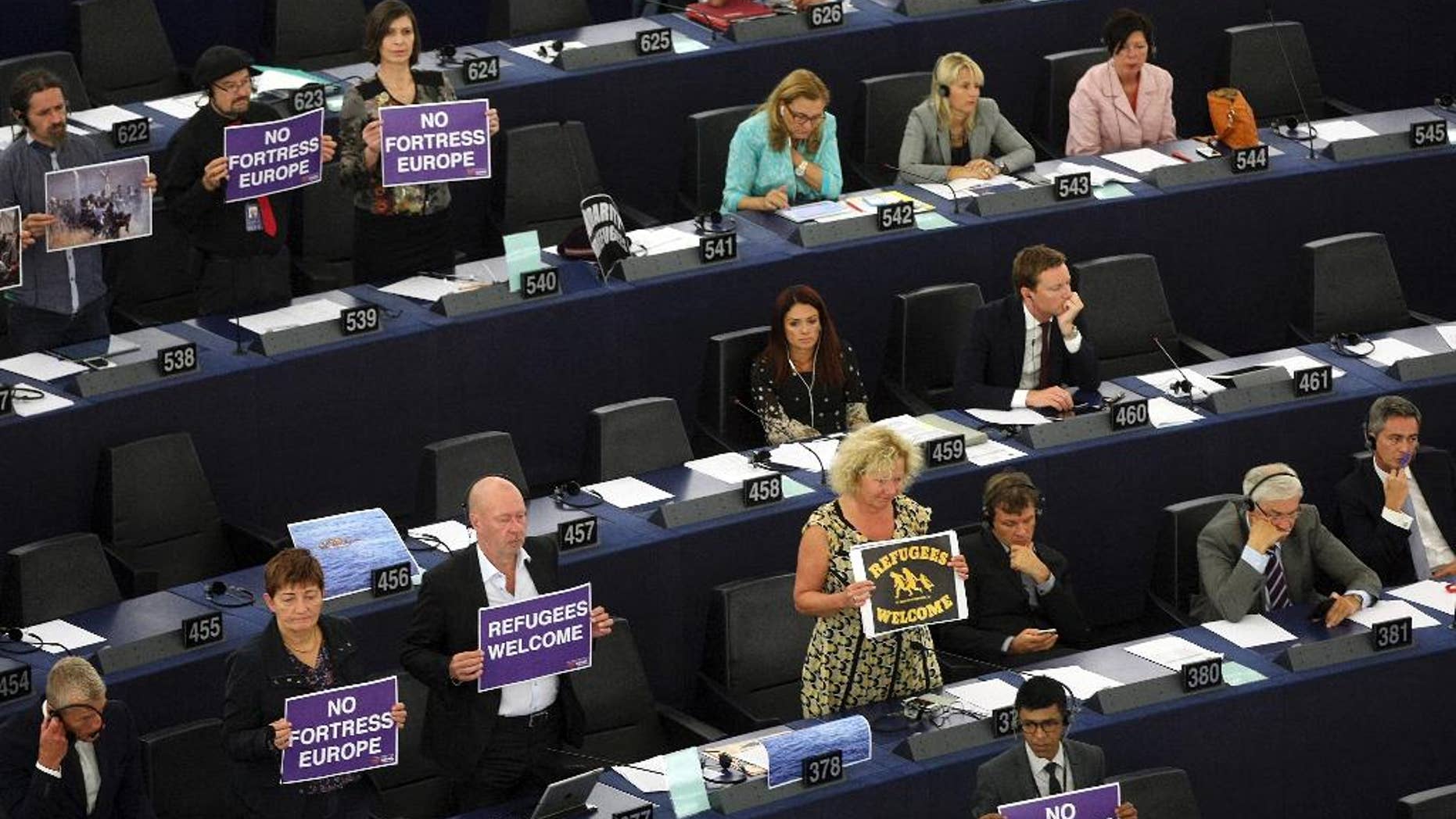 Parliament members holds posters while European Commission President Jean-Claude Juncker delivers his State of the Union address at the European Parliament in Strasbourg, eastern France, Wednesday, Sept.9, 2015. Juncker called on EU countries to agree by next week to share 160,000 refugees, warning that Greece, Italy and Hungary can no longer cope alone. (AP Photo/Christian Lutz)