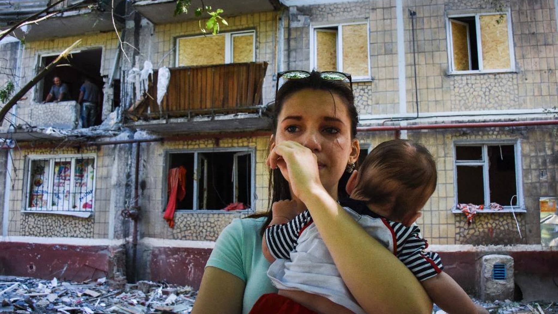 A woman cries as she holds her baby, near to her house damaged by shelling, in Horlivka, eastern Ukraine, Thursday, June 11, 2015. At least four people including a child were killed by shelling in east Ukraine on Thursday. (AP Photo/Mstyslav Chernov)