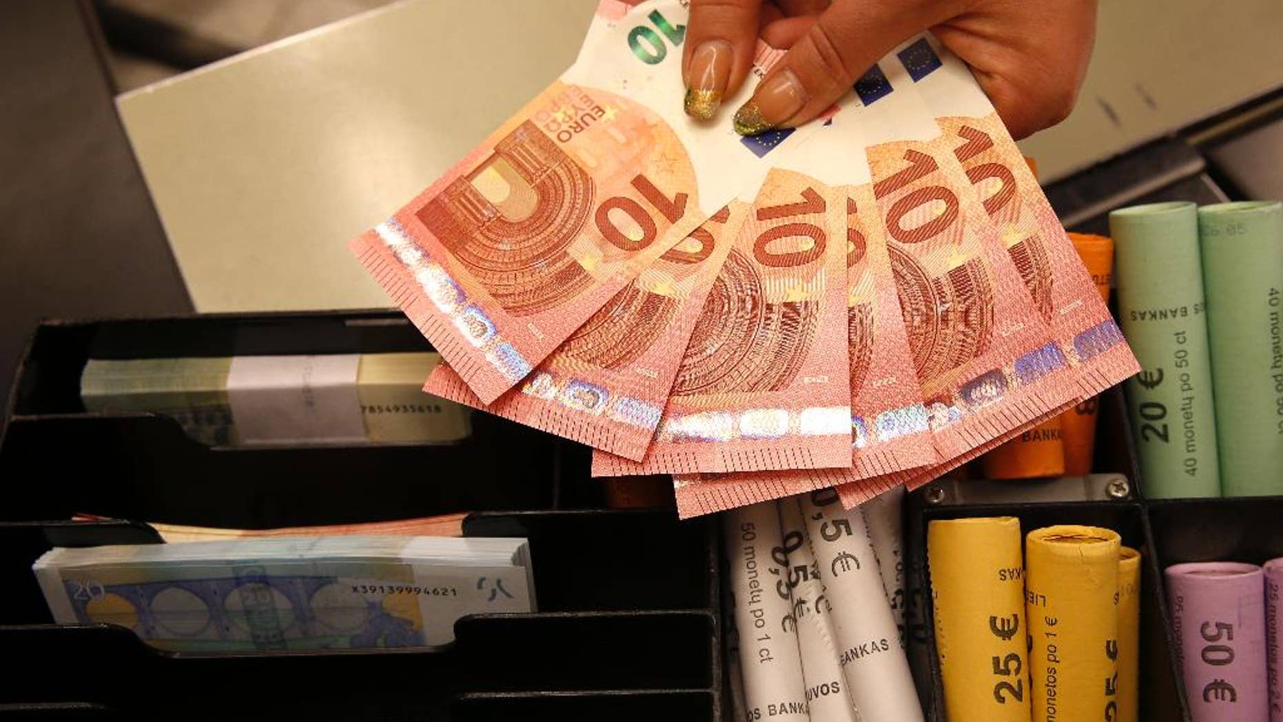 Euro coins and banknotes are shown by a salesclerk at a shop in Vilnius, Lithuania, Thursday, Jan. 1, 2015. The Baltic state of Lithuania early Thursday became the 19th European Union member to adopt the joint European currency, the euro. (AP Photo/Mindaugas Kulbis)