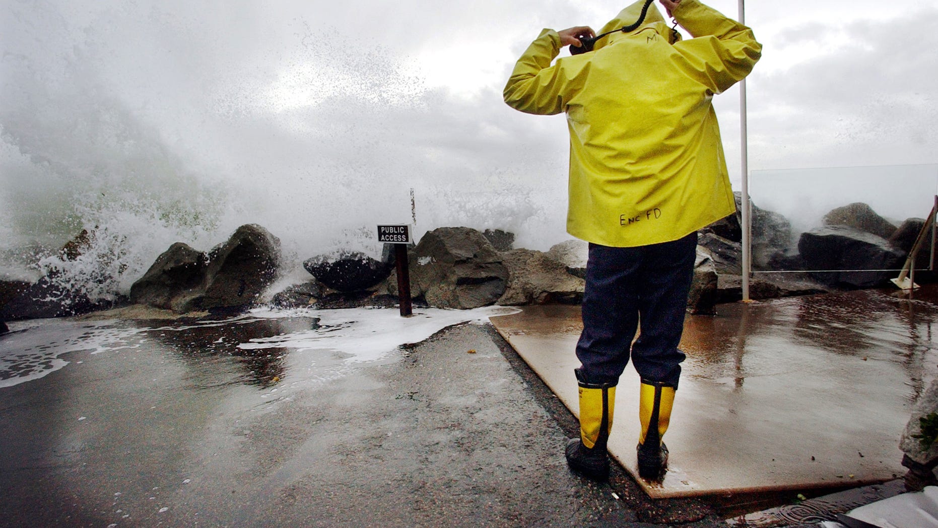 CARDIFF BY THE SEA, CA - DECEMBER 20: Encinitas fireman Mike Kemp adjusts his hood as a wave crashes over a sea wall December 20, 2002 in Cardiff By the Sea, California. Heavy rains and large surf pounded the West Coast as a product of El Nino with the region expecting above average rainfall totals this winter due to El Nino. (Photo by Sandy Huffaker/Getty Images)