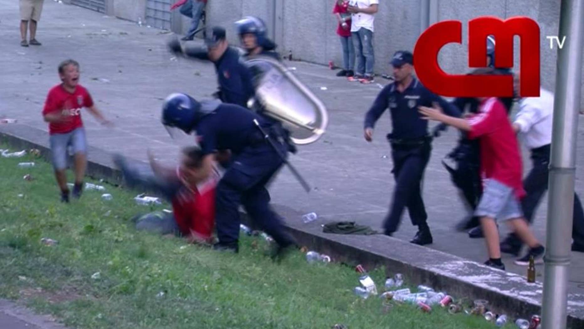 In this screen grab made from video provided by CMTV, a boy cries as his father is attacked by police with batons, outside of a stadium, in Lisbon, Portugal, late Monday, May 18, 2015. Portuguese prosecutors are investigating a policeman who beat a man in front of his young children and punched their grandfather outside a soccer stadium, sparking a national scandal. Police approached Jose Magalhaes, his two sons and his father Sunday outside Guimaraes stadium in northern Portugal, where Benfica had just won the Portuguese league title, according to film footage and witness reports. (CMTV via AP)
