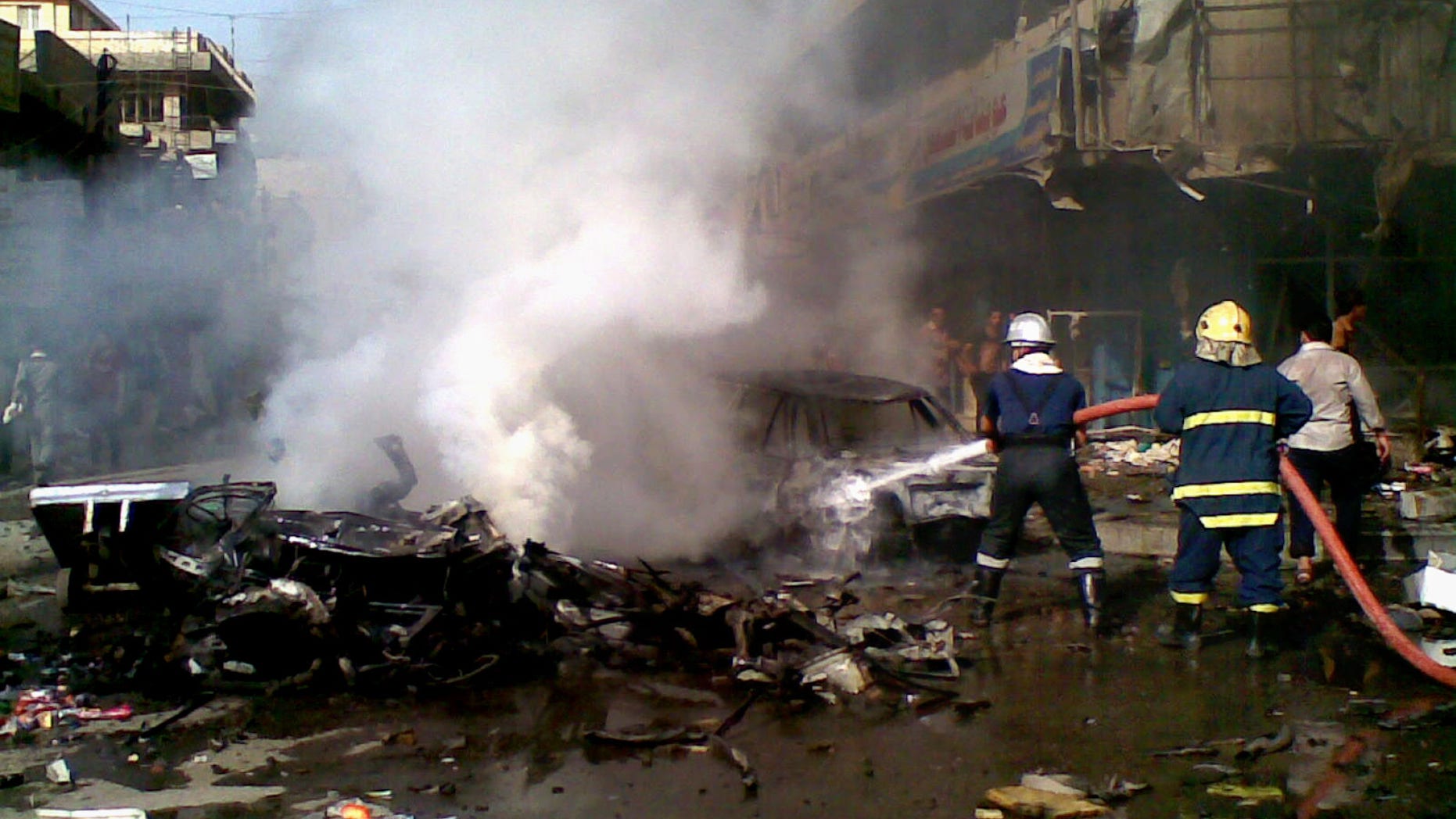 Iraqi firefighters distinguish a fire at the scene of a car bomb attack in Baghdad, Iraq, Monday, May 27, 2013. A parked car bomb explosion in the busy commercial Sadoun Street in central Baghdad, killed and wounded scores of people, police said. (AP Photo)