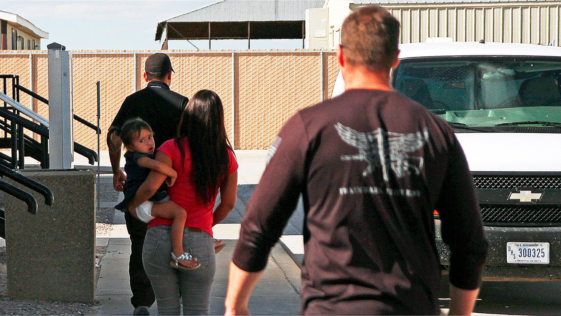 A woman and child are escorted to a van by detention facility guards inside the Artesia Family Residential Center.