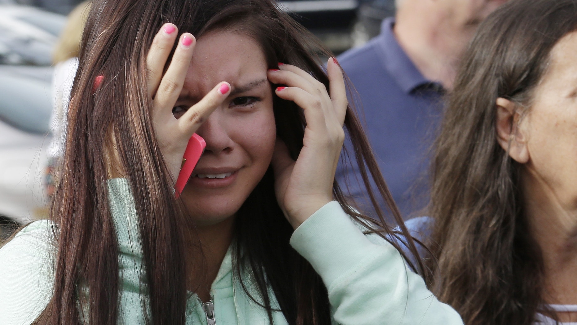 A young woman cries as she waits at a church, Friday, Oct. 24, 2014, where students were taken to be reunited with parents following a shooting at Marysville Pilchuck High School in Marysville, Wash.