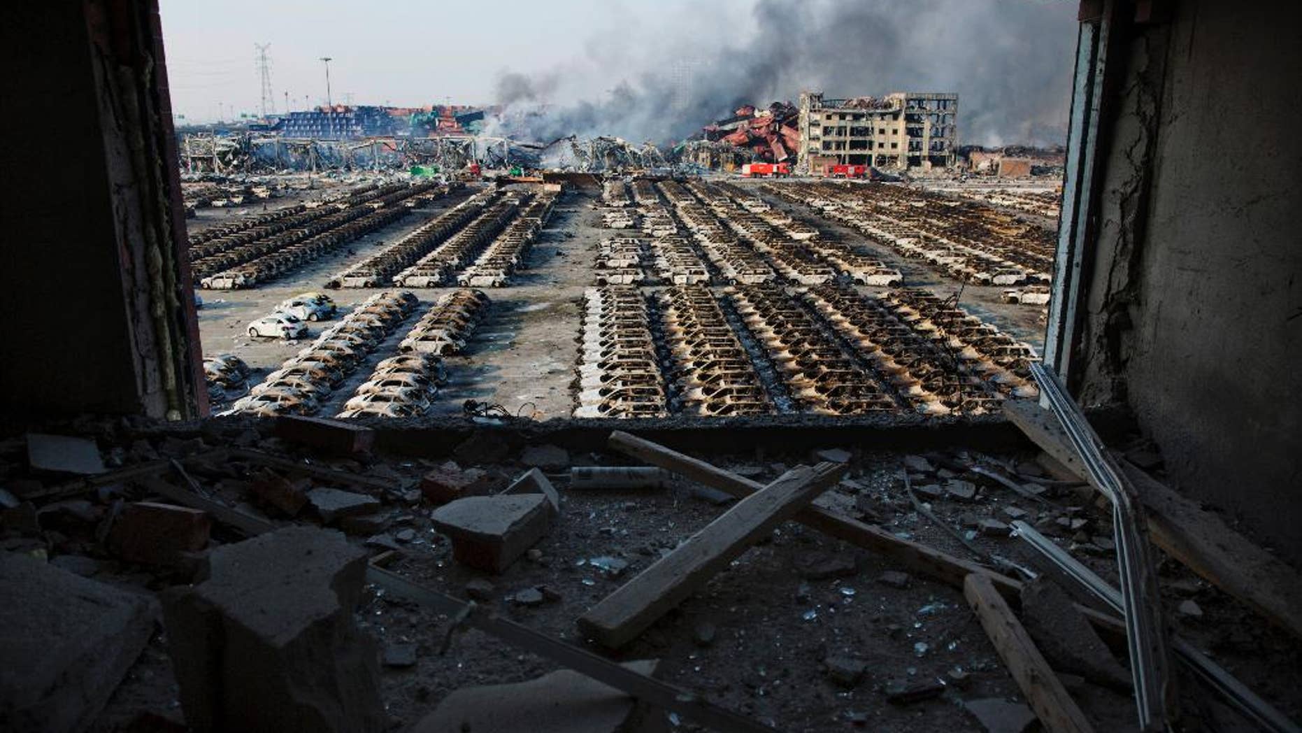 FILE - In this Aug. 13, 2015 photo, a shattered window frames the site of an explosion at a port warehouse in northeastern China's Tianjin municipality. Chinese prosecutors have detained 11 government officials and company executives over a massive warehouse explosion that killed at least 139 people in the country's worst industrial disaster in recent years. (AP Photo/Ng Han Guan. File)