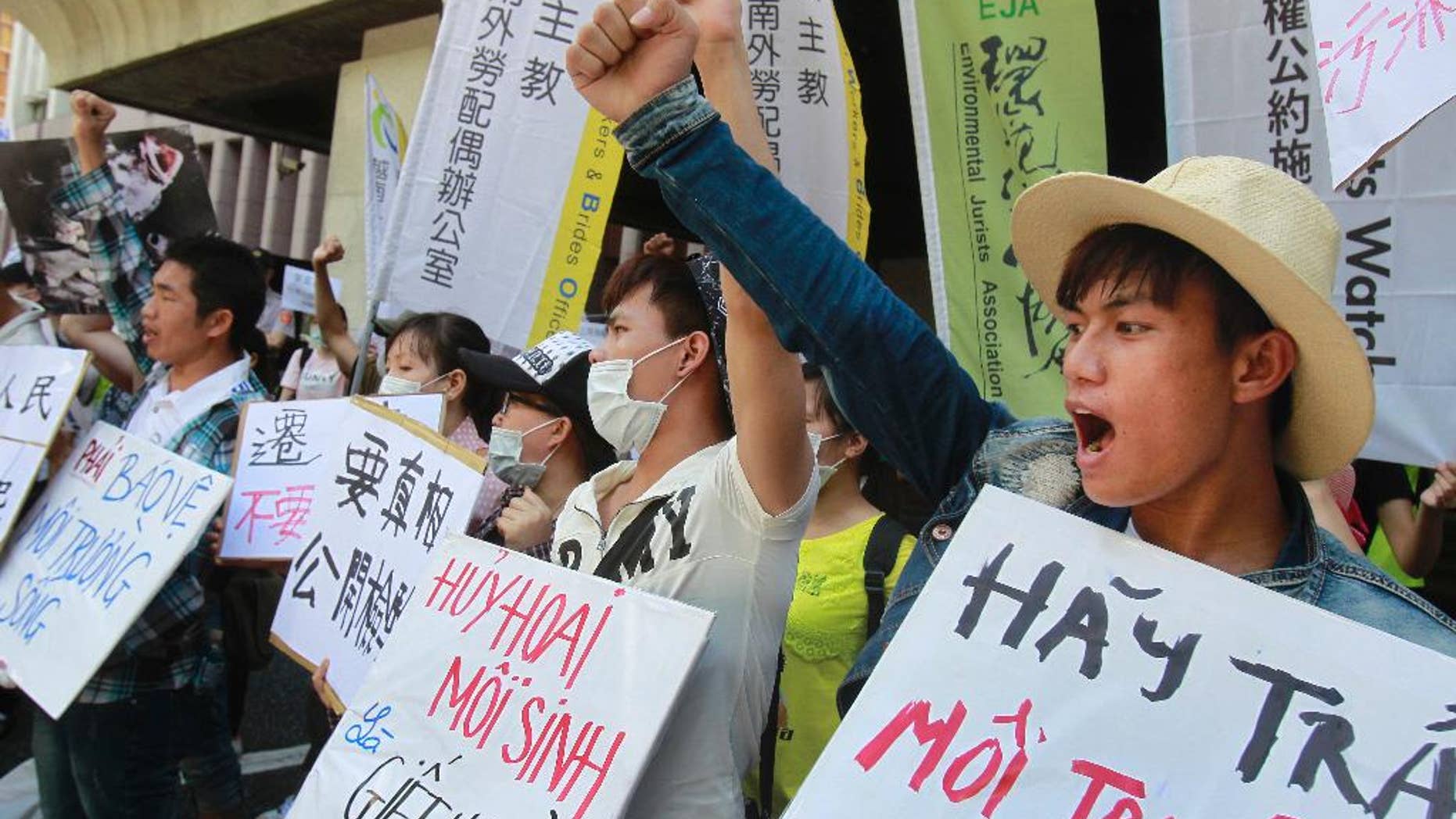 FILE - In this Aug. 10, 2016 file photo, Vietnamese activists shout slogans and hold placards reading ''Destroying the environment is killing, "left, and ''Return clean seawater to us'' during a protest to urge Formosa Plastics Group to take responsibilities for the cleanup in Vietnam, in Taipei, Taiwan. Hundreds of Vietnamese fishermen have filed claims seeking compensation from a Taiwanese steel company that acknowledged its toxic chemicals caused a massive fish kill, a local priest helping the fishermen said Tuesday, Sept. 27, 2016. (AP Photo/Chiang Ying-ying, File)