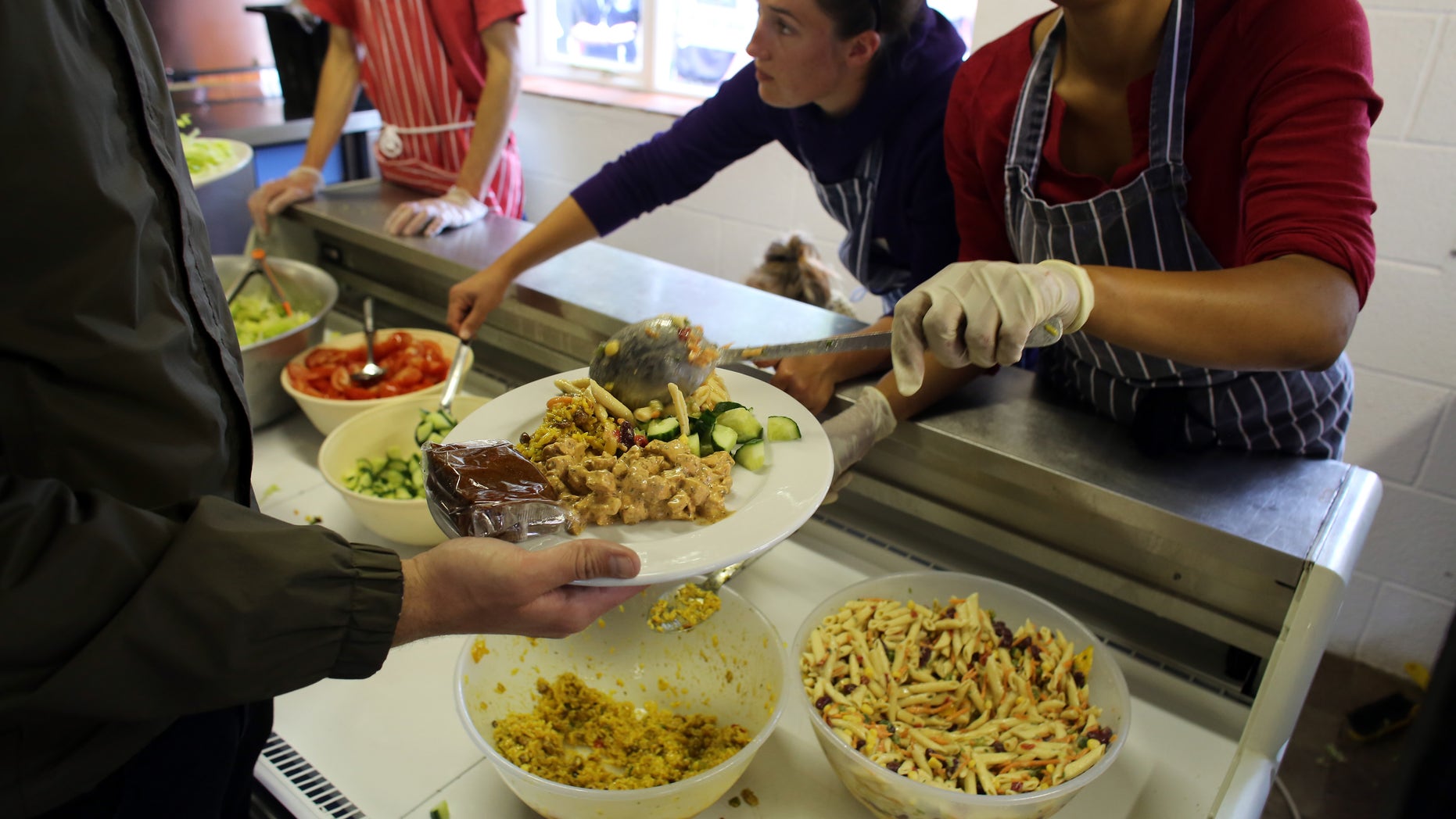 GLASTONBURY, ENGLAND - JUNE 20: Festival caterers serve lunch at Goose Hall, the on-site staff canteen, at the Glastonbury Festival of Contemporary Performing Arts site at Worthy Farm, in Pilton on June 20, 2013 in Glastonbury, England. In a weeks time, the diary farm in Somerset will be playing host to one of the largest music festivals in the world and this year features headline acts Artic Monkeys, Mumford and Sons and the Rolling Stones. Tickets to the event which is now in its 43rd year sold out in minutes and that was before any of the headline acts had been confirmed. The festival, which started in 1970 when several hundred hippies paid 1 GBP to watch Marc Bolan, now attracts more than 175,000 people over five days. (Photo by Matt Cardy/Getty Images)