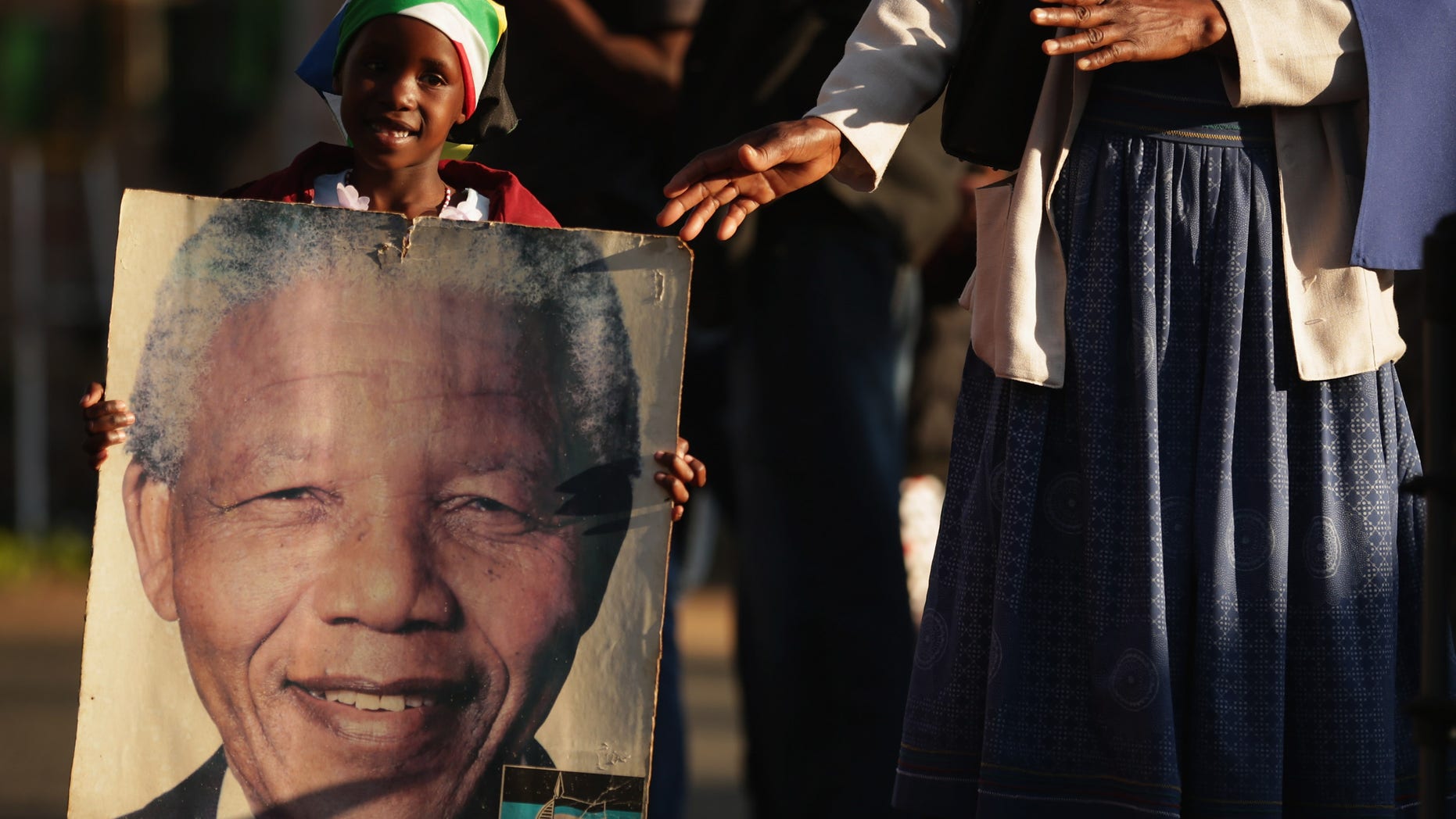 PRETORIA, SOUTH AFRICA - JULY 03: Lehlogonolo Nkosi, 7, carries a photograph of former South African President Nelson Mandela outside the Mediclinic Heart Hospital where Mandela is being treated for a recurring lung infection July 3, 2013 in Pretoria, South Africa. The anti-apartheid icon and Nobel Peace Prize laureate has been in critical condition at the hospital for more than three weeks. (Photo by Chip Somodevilla/Getty Images)