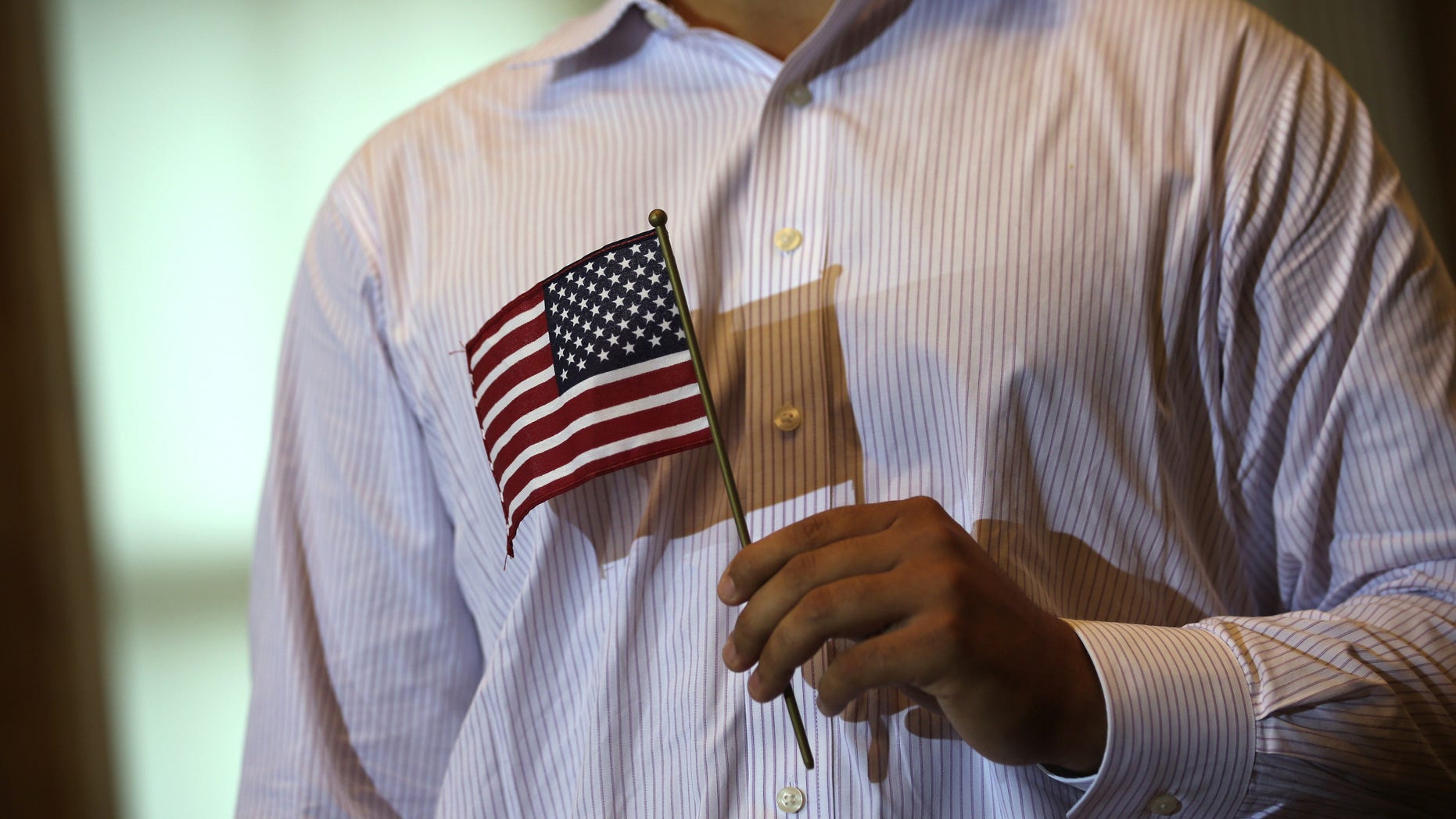 WASHINGTON, DC - JULY 03: A new U.S. citizen holds a U.S. flag during a naturalization ceremony at the Treasury Department July 3, 2013 in Washington, DC. More than 7,800 people will become citizens at more than 100 special ceremonies, as part of the United States Citizenship and Immigration Services' (USCIS) annual celebration of Independence Day, across the country and around the world from July 1 to July 5. (Photo by Alex Wong/Getty Images)