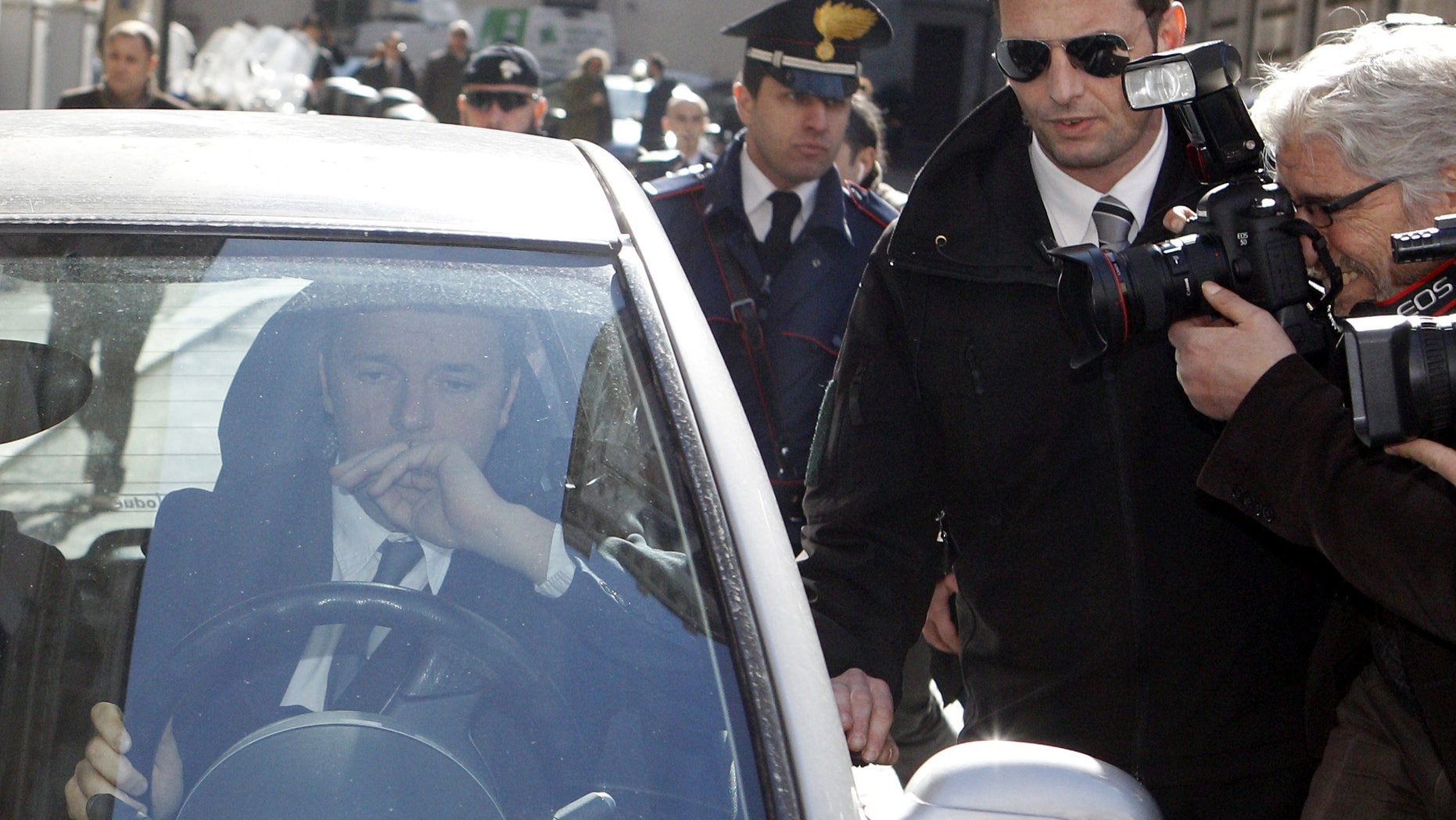 Florence Mayor and Italian center-left Democratic Party leader Matteo Renzi drives away as he is chased by reporters following a meeting with Premier Enrico Letta at Chigi Palace government office, in Rome, Wednesday, Feb. 12, 2014. Letta battled Wednesday to stay in office amid a power play by supporters of the dynamic head of his party, Renzi, to replace him as premier in the latest chapter to convulse Italy's fragile political stability. Renzi arrived at Letta's office at Palazzo Chigi for a make-or-break meeting ahead of a Democratic Party summit on Thursday that is expected to determine the government's next steps. (AP Photo/Riccardo De Luca)