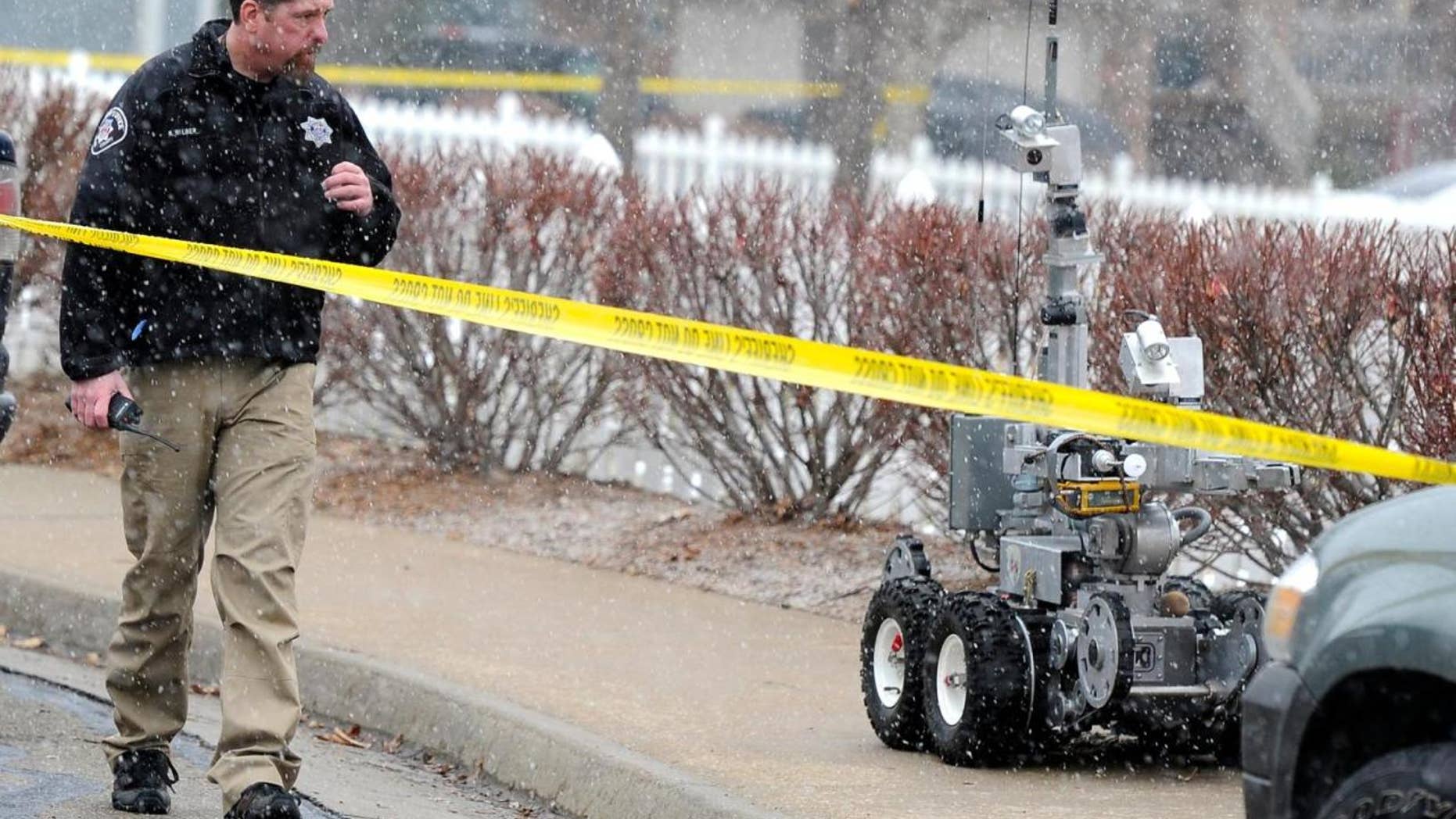 Jan. 7, 2012: A police officer walks beside a robot used in bomb situations as he responds to an explosion in a car Saturday near 337 Lodgewood Point in Lafayette, Colo.