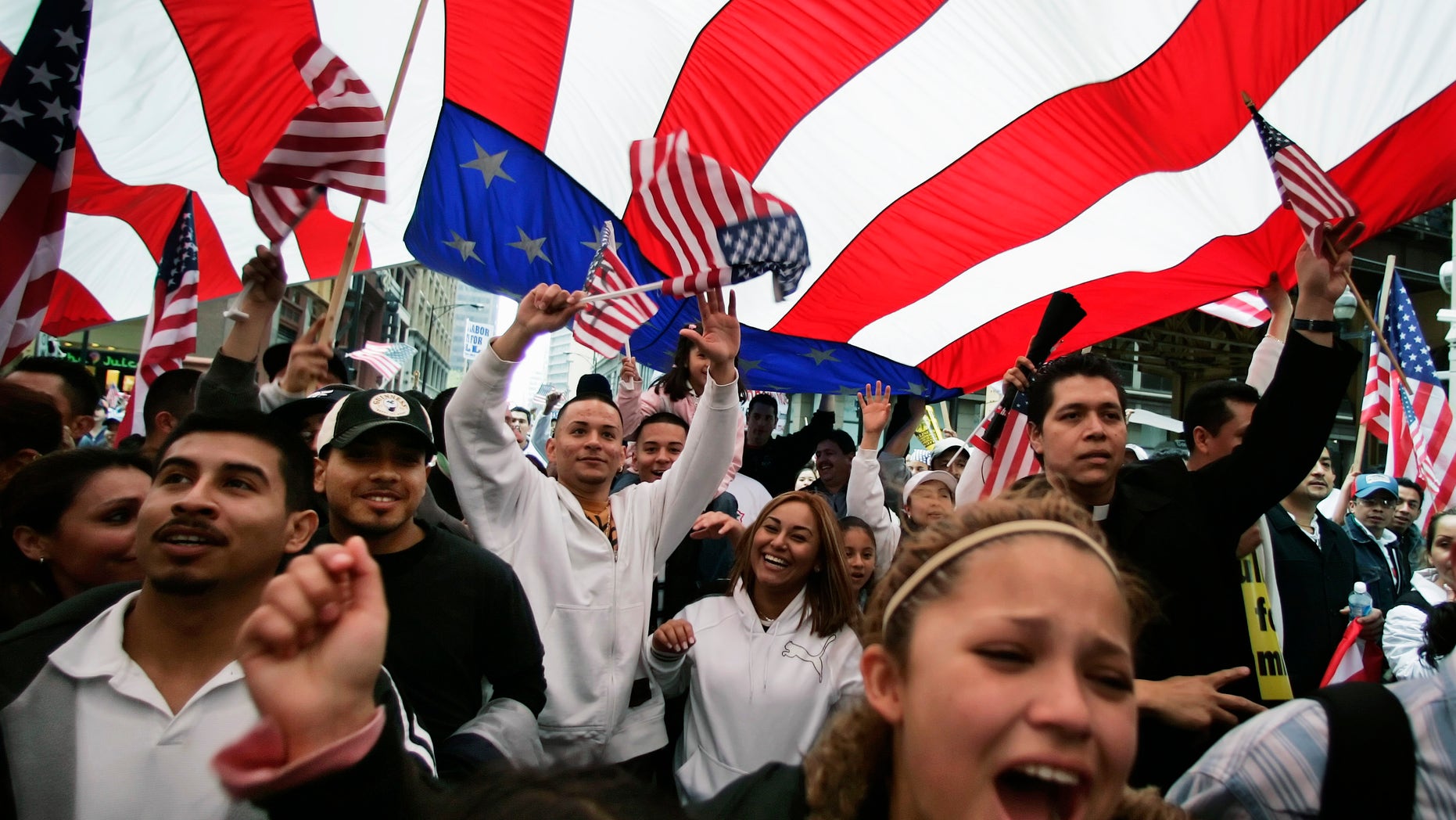 FILE - In this May 1, 2006 file photo, participants in an immigration rights rally walk under a giant American flag during a march through downtown Chicago. Figures released by the U.S. Census Bureau Tuesday, Feb. 15, 2011, show that while Illinois' populations of both whites and blacks decreased, the population of people who identified themselves as Hispanic grew at a sharp 32.5 percent rate. (AP Photo/M. Spencer Green, File)